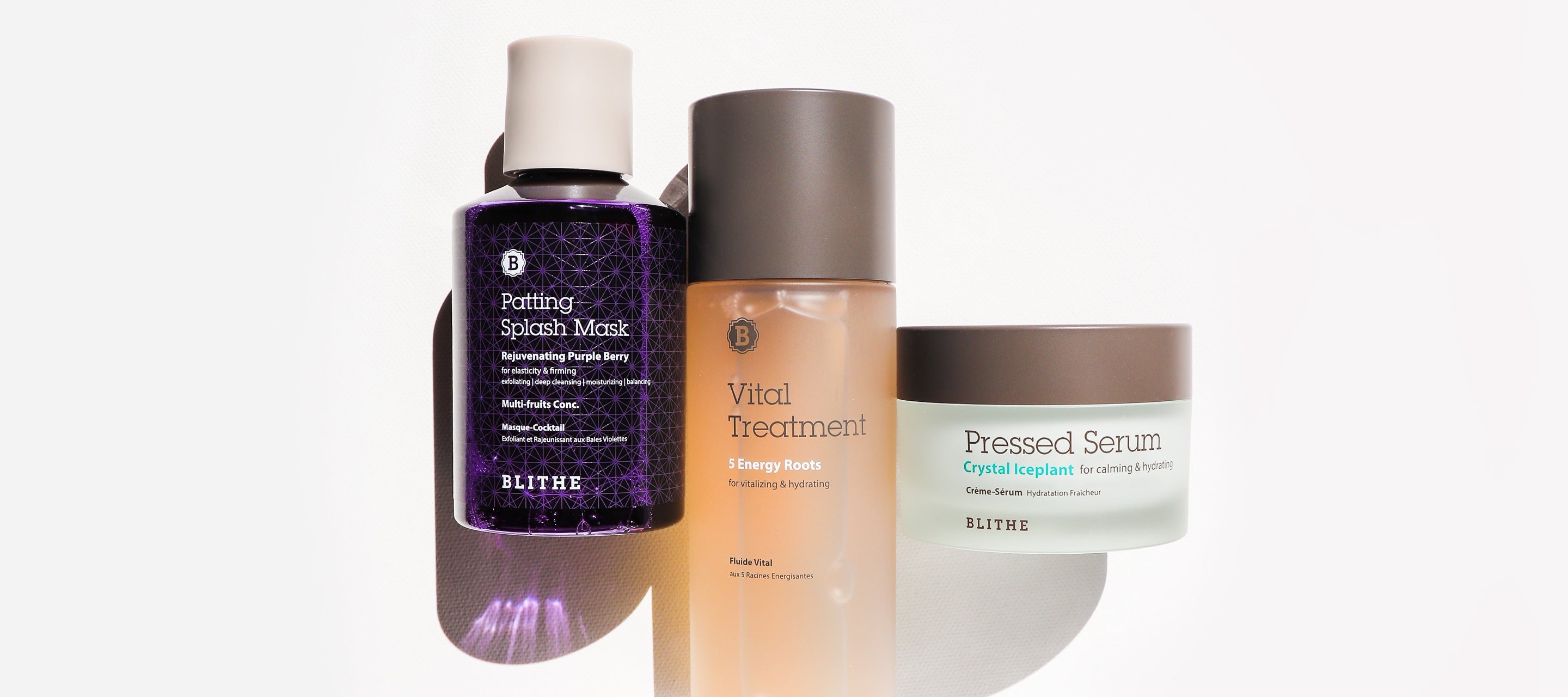 Three BLITHE skincare products displayed together: a purple Patting Splash Mask, an amber Vital Treatment bottle, and a teal Pressed Serum jar.