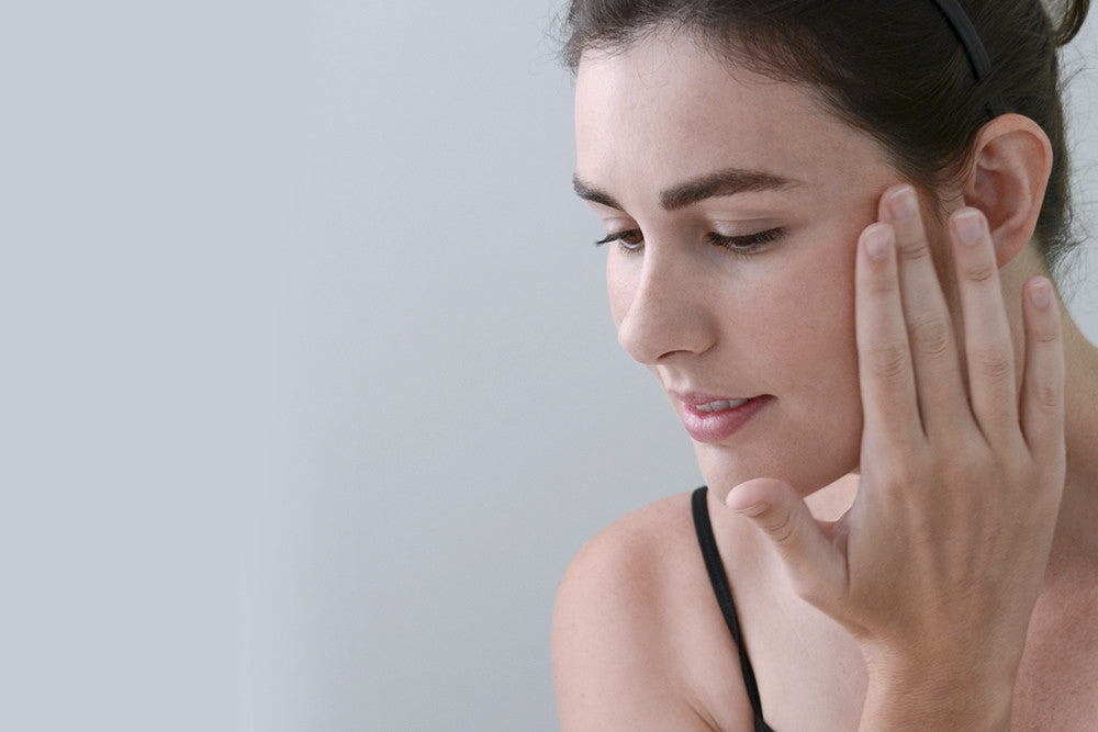 Woman carefully applying or checking skincare product on her face.