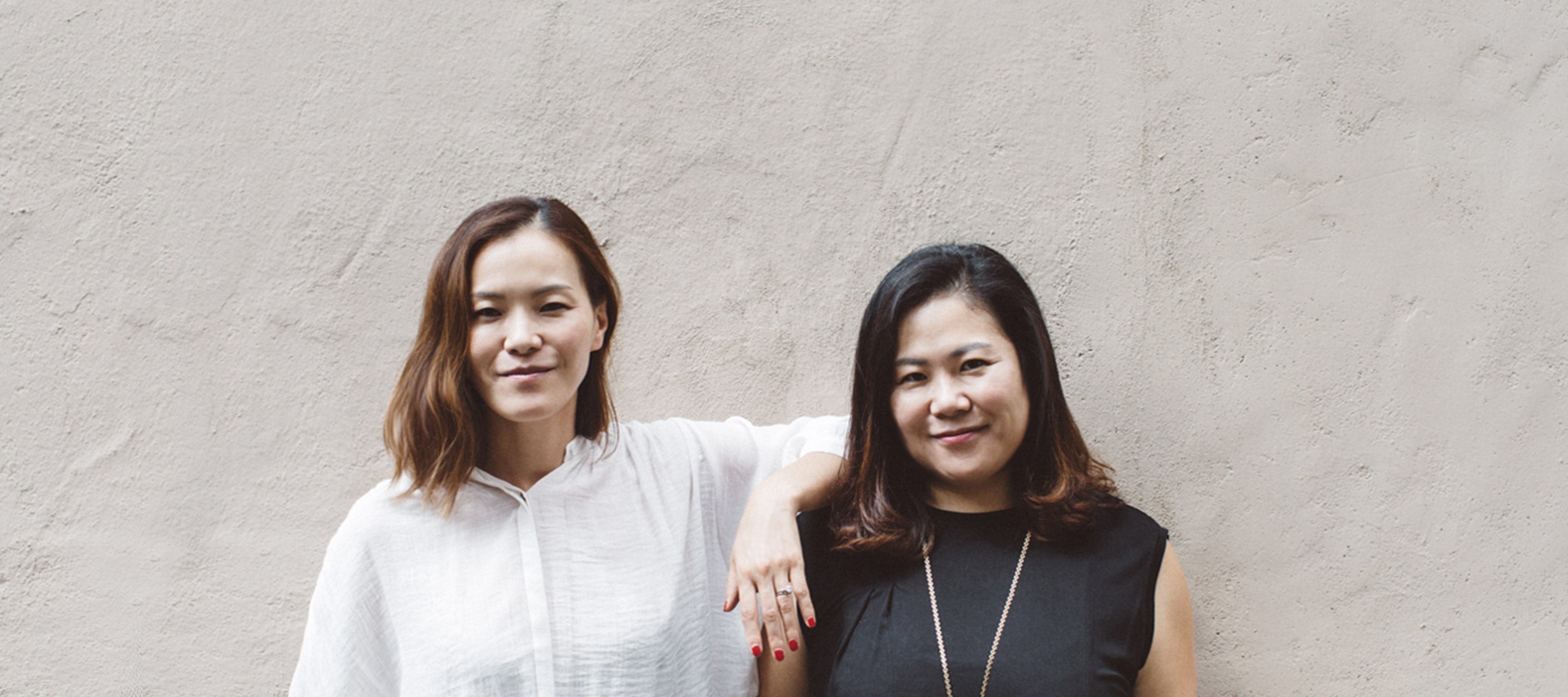 Sue and Herra, the co-founders of Ohlolly K-Beauty, posing together in front of a neutral background, highlighting their women-owned small business.
