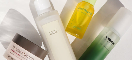A collection of four K-beauty skincare products, including serums and a moisturizer, arranged on a white surface with soft shadows.