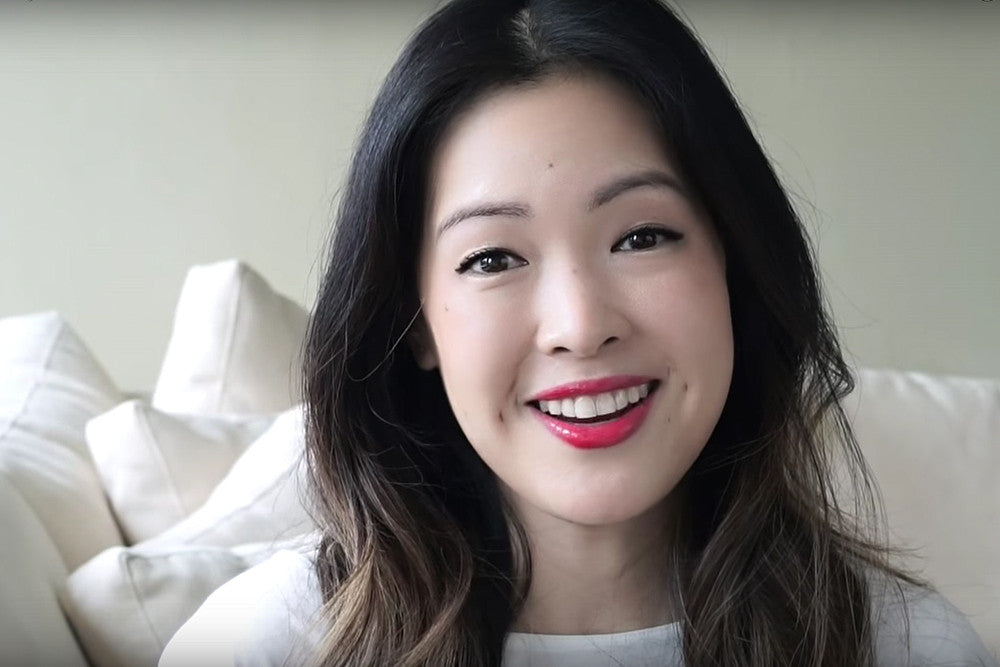 Headshot of a smiling female beauty vlogger with bright red lipstick.