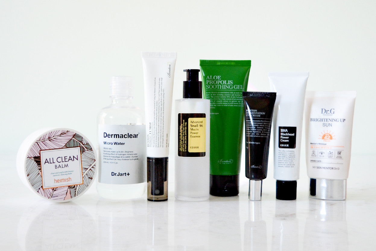 A flat lay photo of nine different Korean skincare products in various bottles and tubes, including Dr. Jart+ Dermaclear, COSRX, and B.T.X.