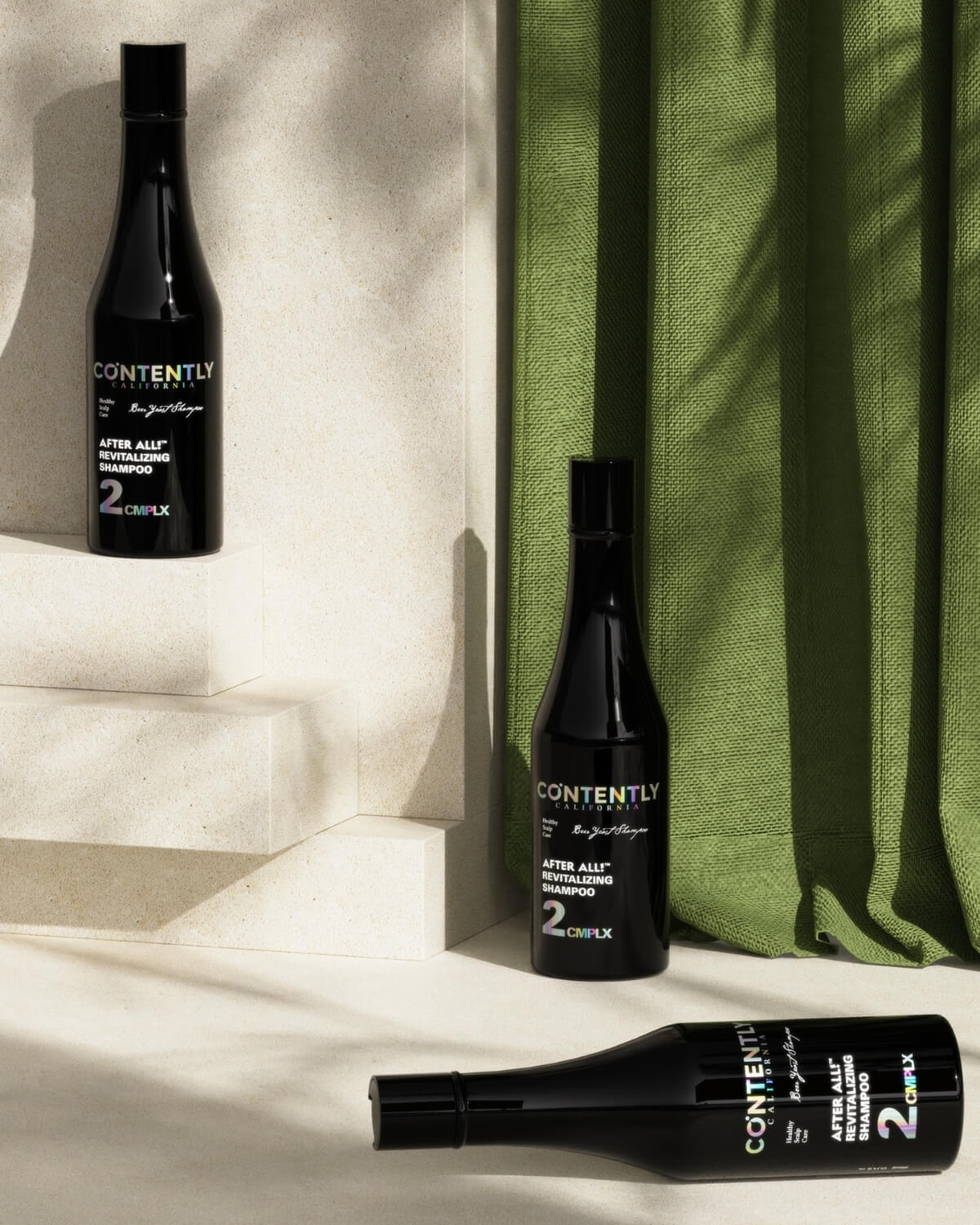 A tropical-inspired studio shot with three shampoo bottles arranged on white steps, featuring a green curtain and the shadow of a palm leaf.