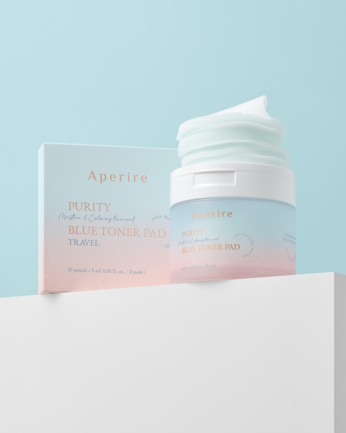 The large container of toner pads sits next to its small, ombre-designed outer box, which indicates a "Travel" version with individual sachets. The products are displayed on a white block against a light blue background.