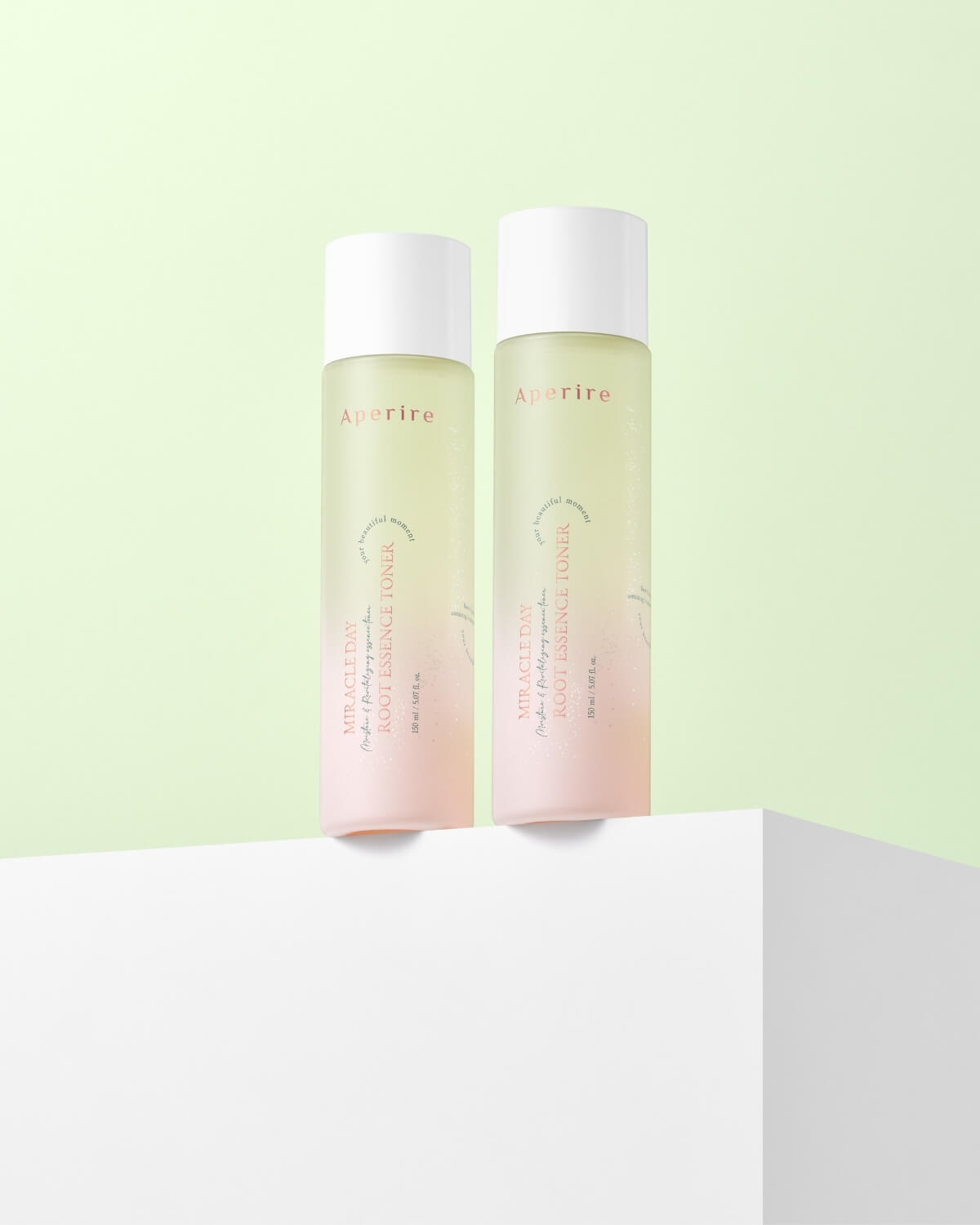 A wide-angle, high-key shot showing the toner bottle and a matching small, white cardboard box for the product, both on a textured white surface next to a single cotton pad and a sprig of greenery.