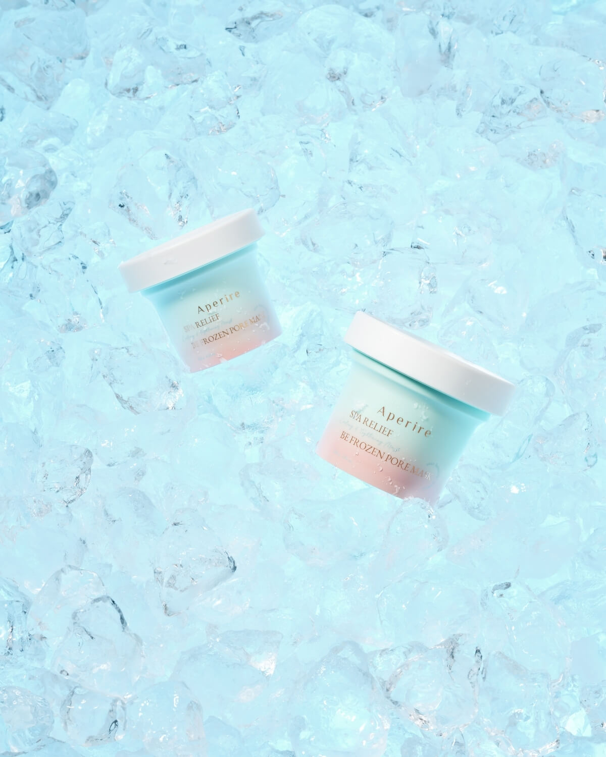 Two jars of Aperire Spa Relief Be Frozen Pore Mask, a cooling and tightening clay mask, resting on a bed of blue ice.