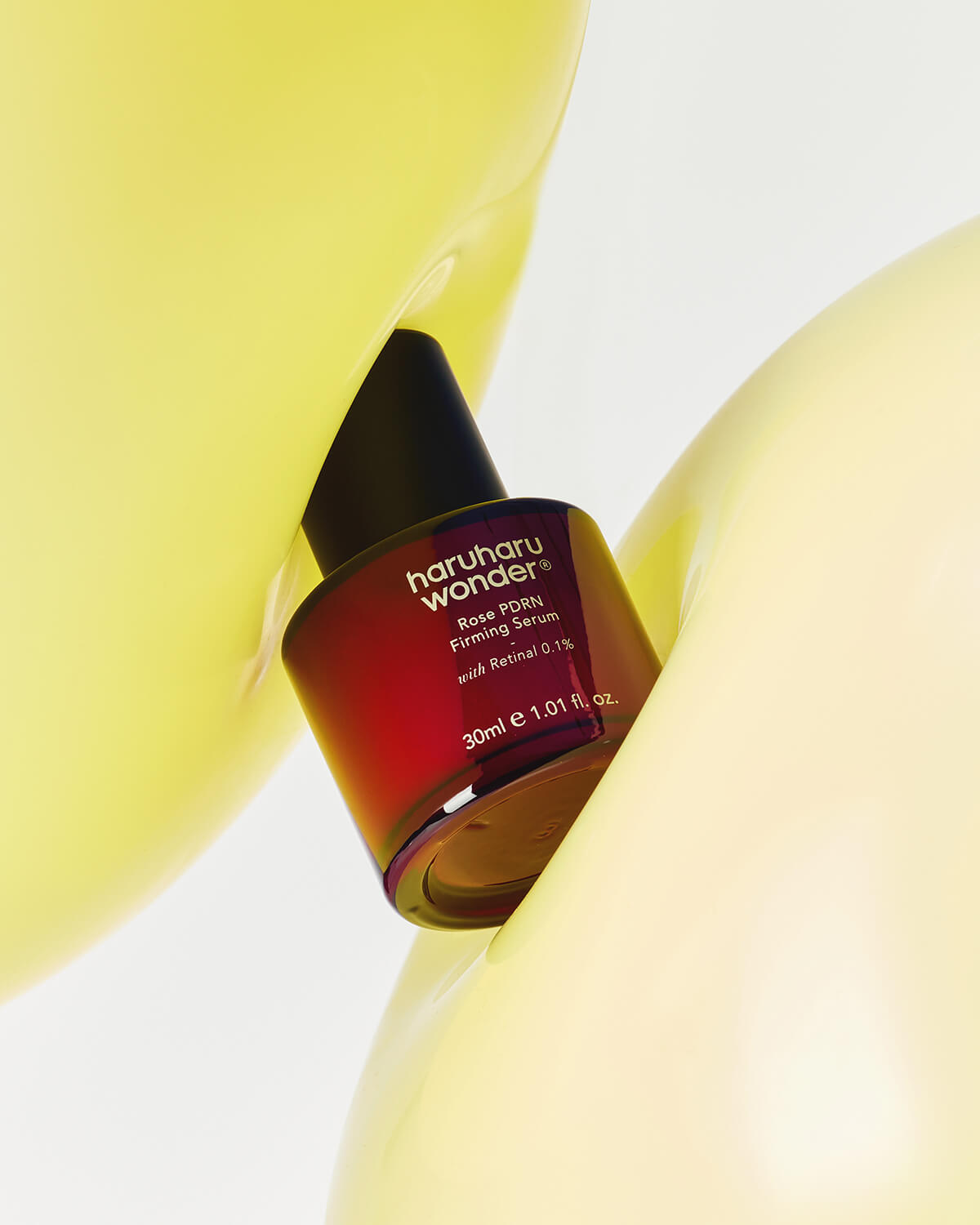 Haruharu Wonder Rose PDRN Firming Serum bottle artistically placed between smooth yellow shapes.
