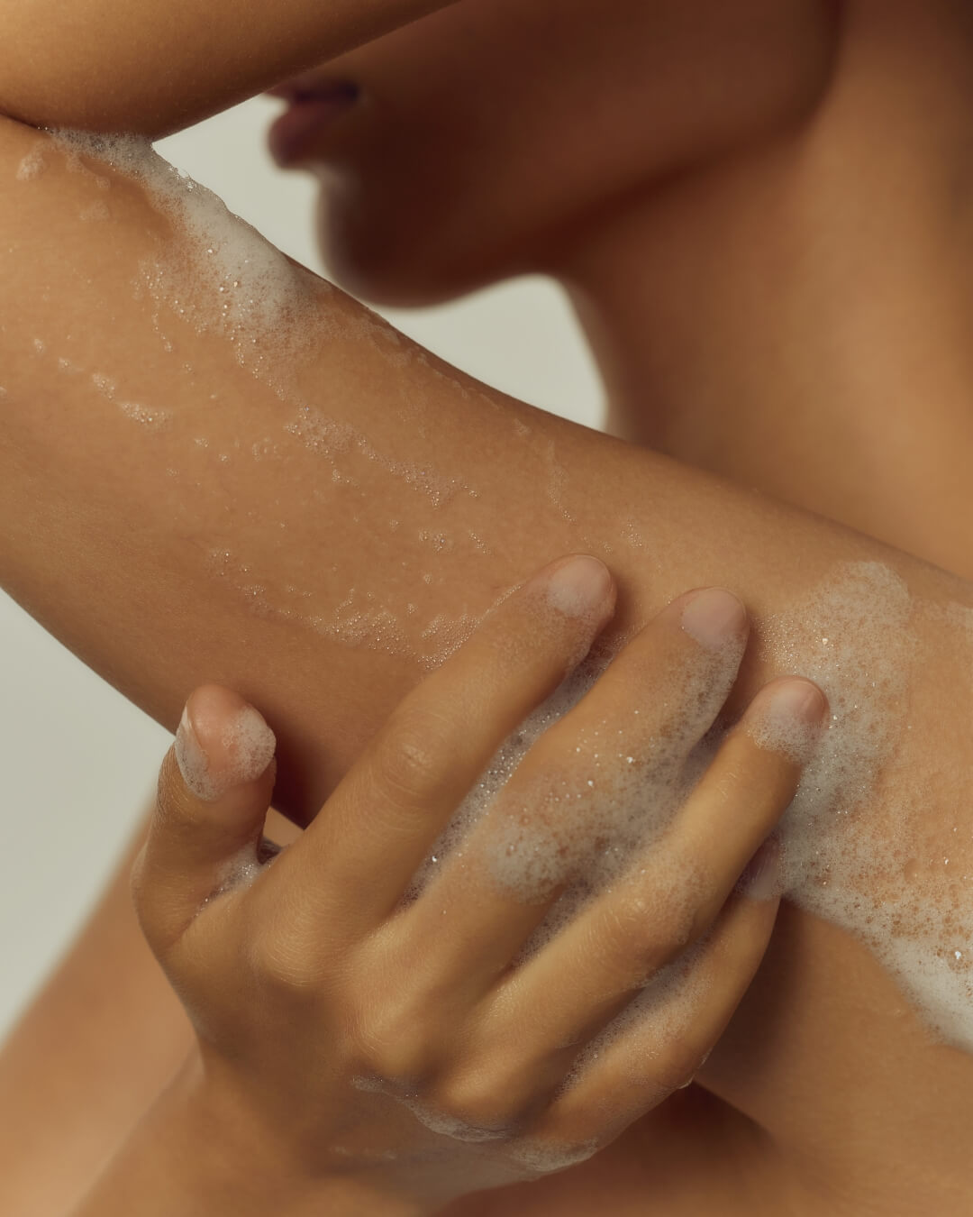 Close up of rich soapy lather being applied to skin during a shower.