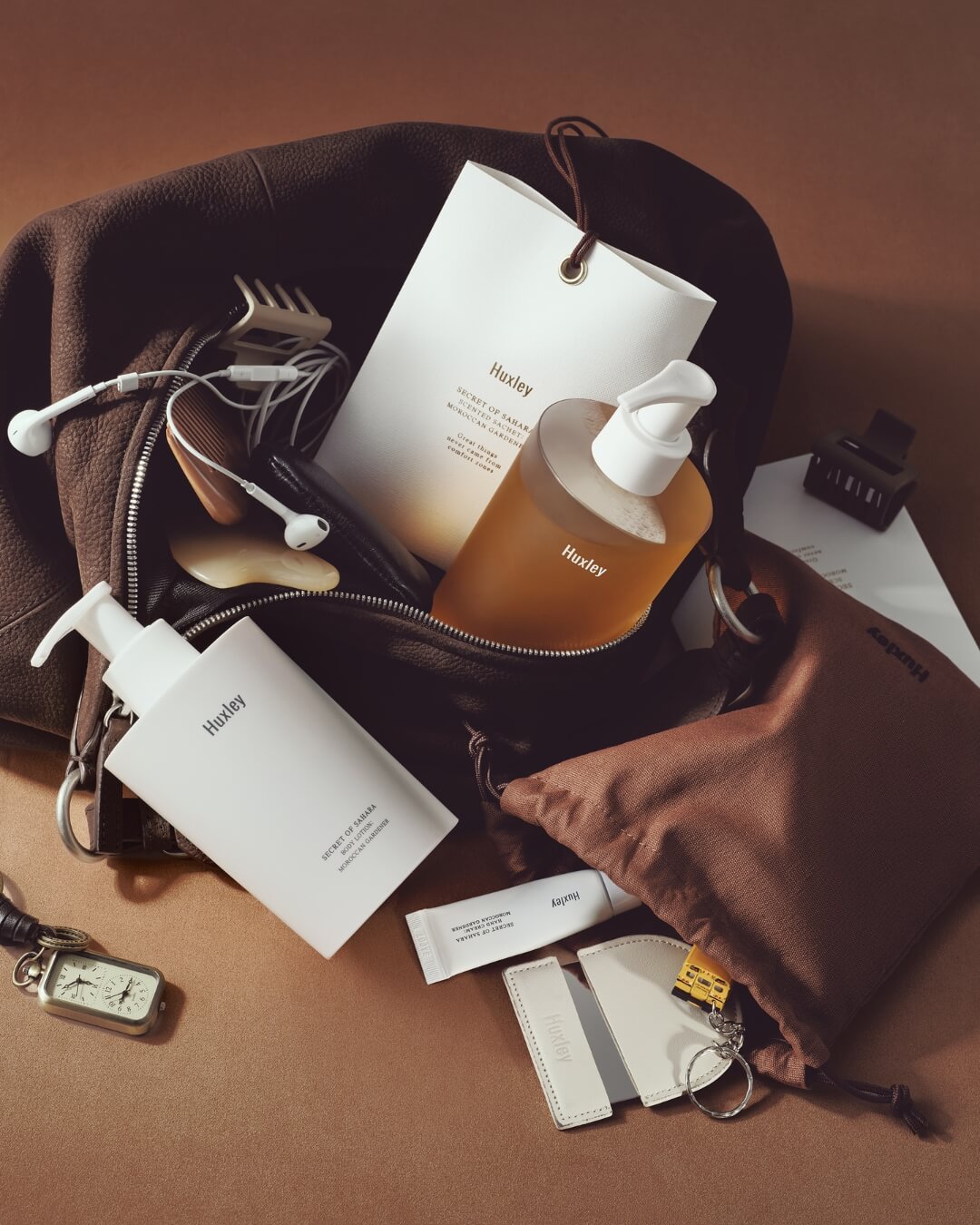 Huxley body care products, including Moroccan Gardener body lotion, packed in a brown travel bag.