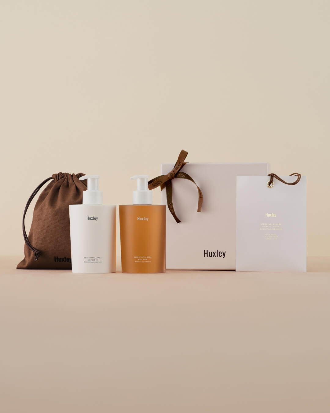 Huxley body lotion and body wash gift set with packaging box, gift bag, and a brown pouch.