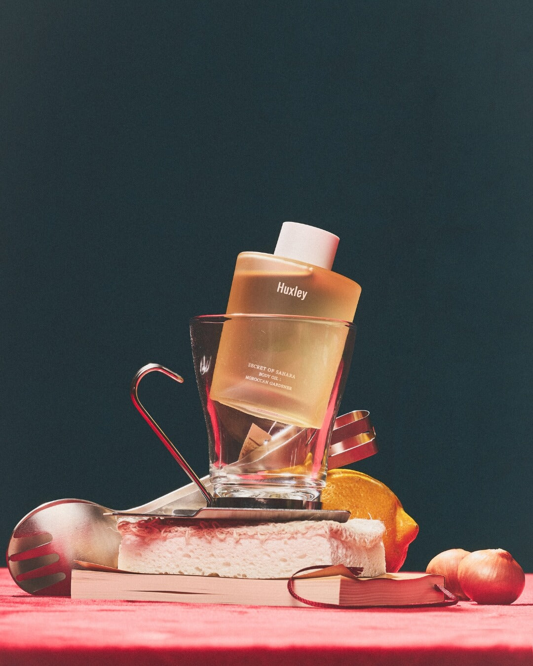 Huxley body oil bottle placed inside a glass cup as part of an artistic lifestyle arrangement.
