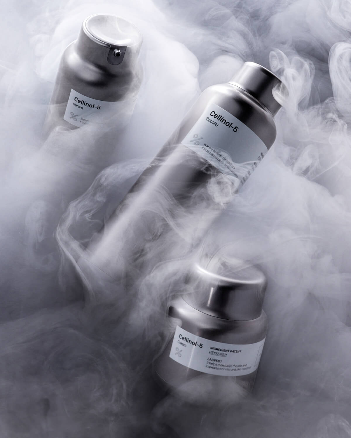 Three bottles of Percent Science Cellinol-5 Booster Essence are artfully arranged amidst swirling white mist, suggesting a scientific or cooling effect.