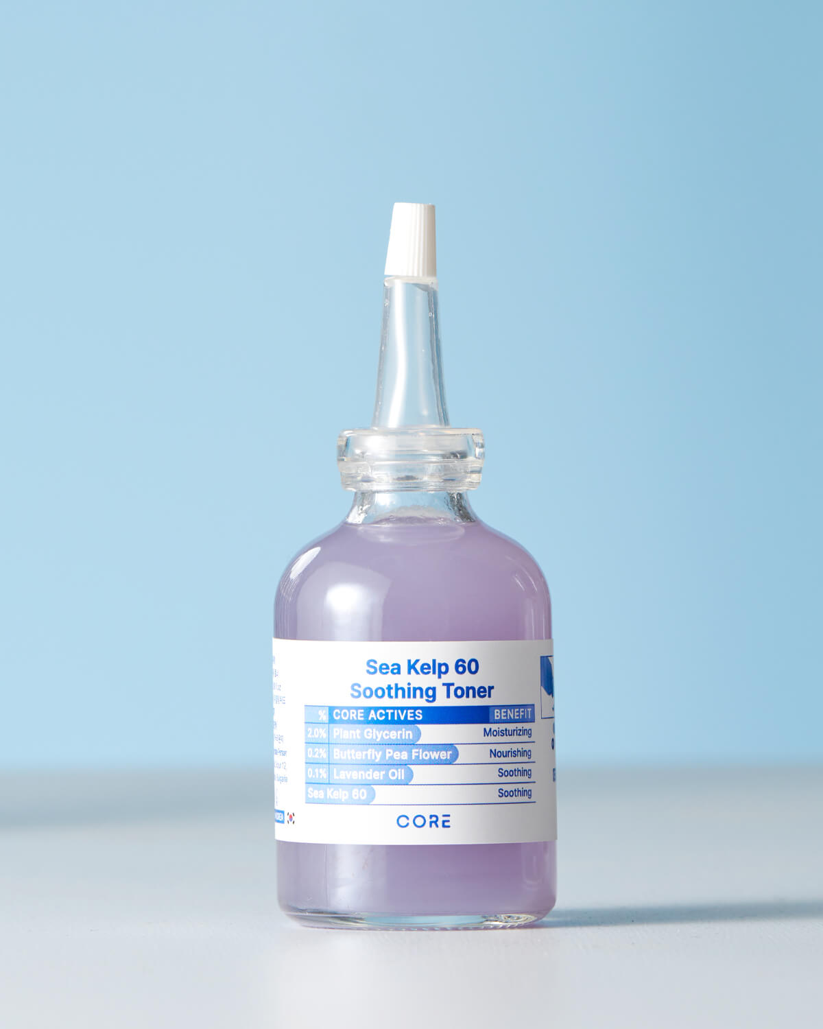A clear, small bottle of Core Sea Kelp 60 Soothing Toner against a light blue background. The toner has a pale lavender color and the label highlights Sea Kelp 60, 2.0% Plant Glycerin, 0.2% Butterfly Pea Flower, and 0.1% Lavender Oil as core actives.