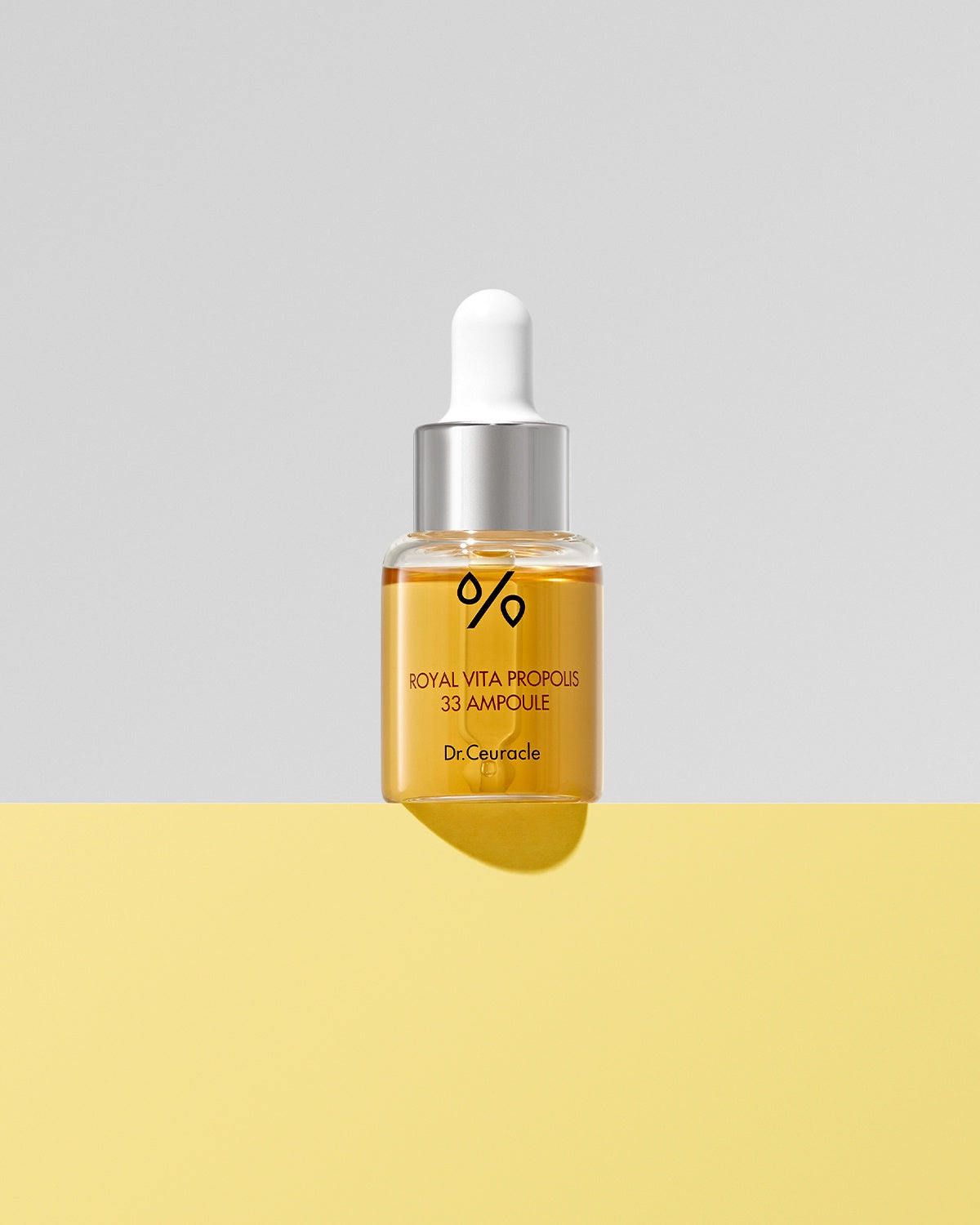 Dr. Ceuracle Royal Vita Propolis 33 Ampoule with dropper cap on a bright yellow and gray background. Propolis skincare.