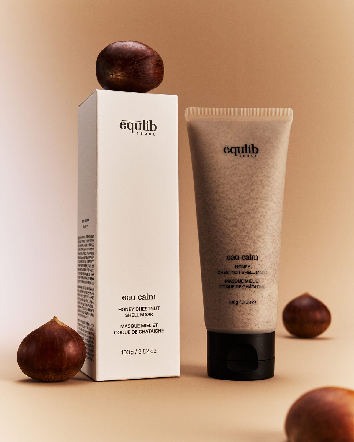 Equlib Eau Calm Honey Chestnut Shell Mask tube standing next to its product packaging box with chestnuts nearby.