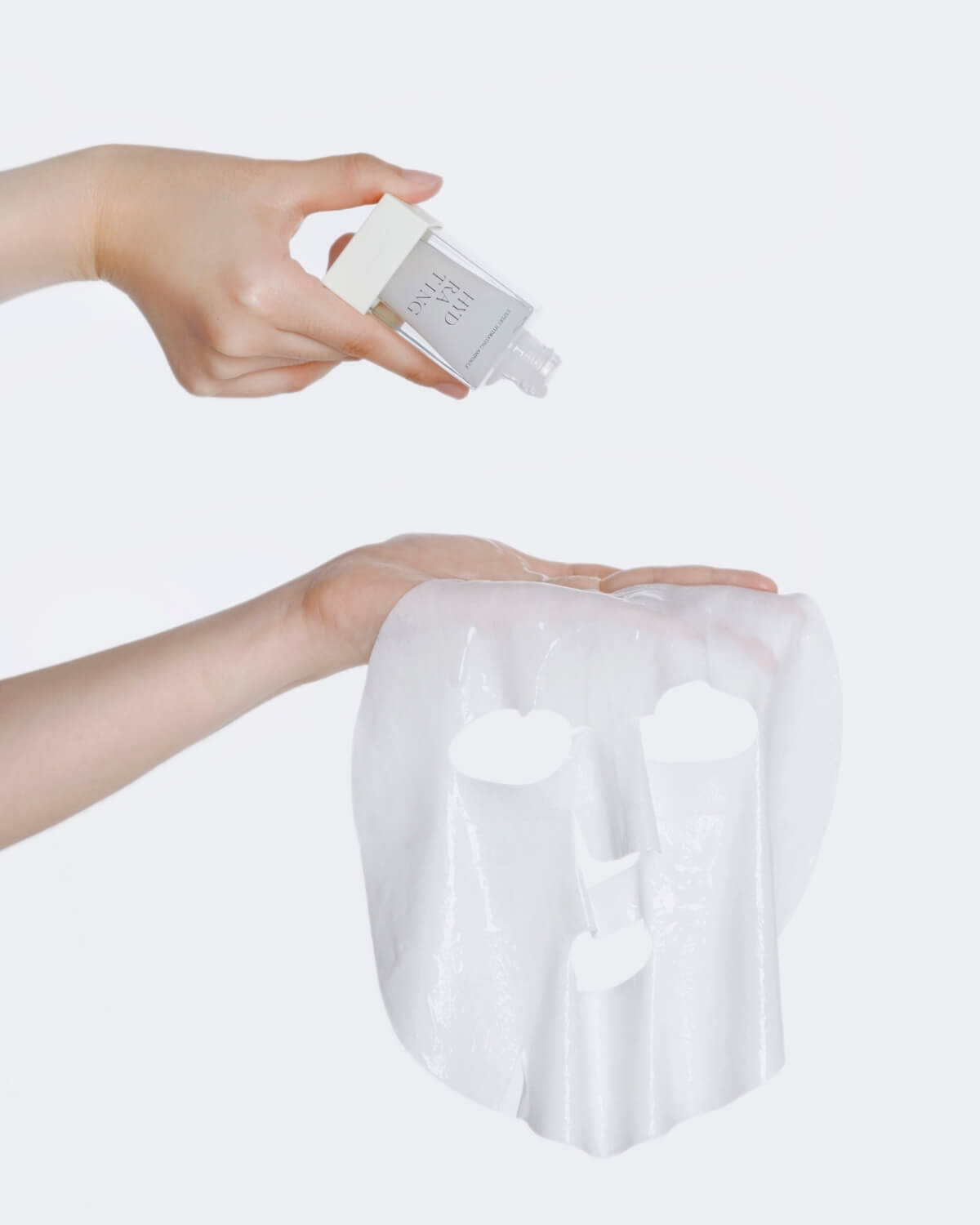 Hand squeezing essence onto the saturated white AIPPO Expert Hydrating Mask sheet. Deeply moisturizing K-beauty mask