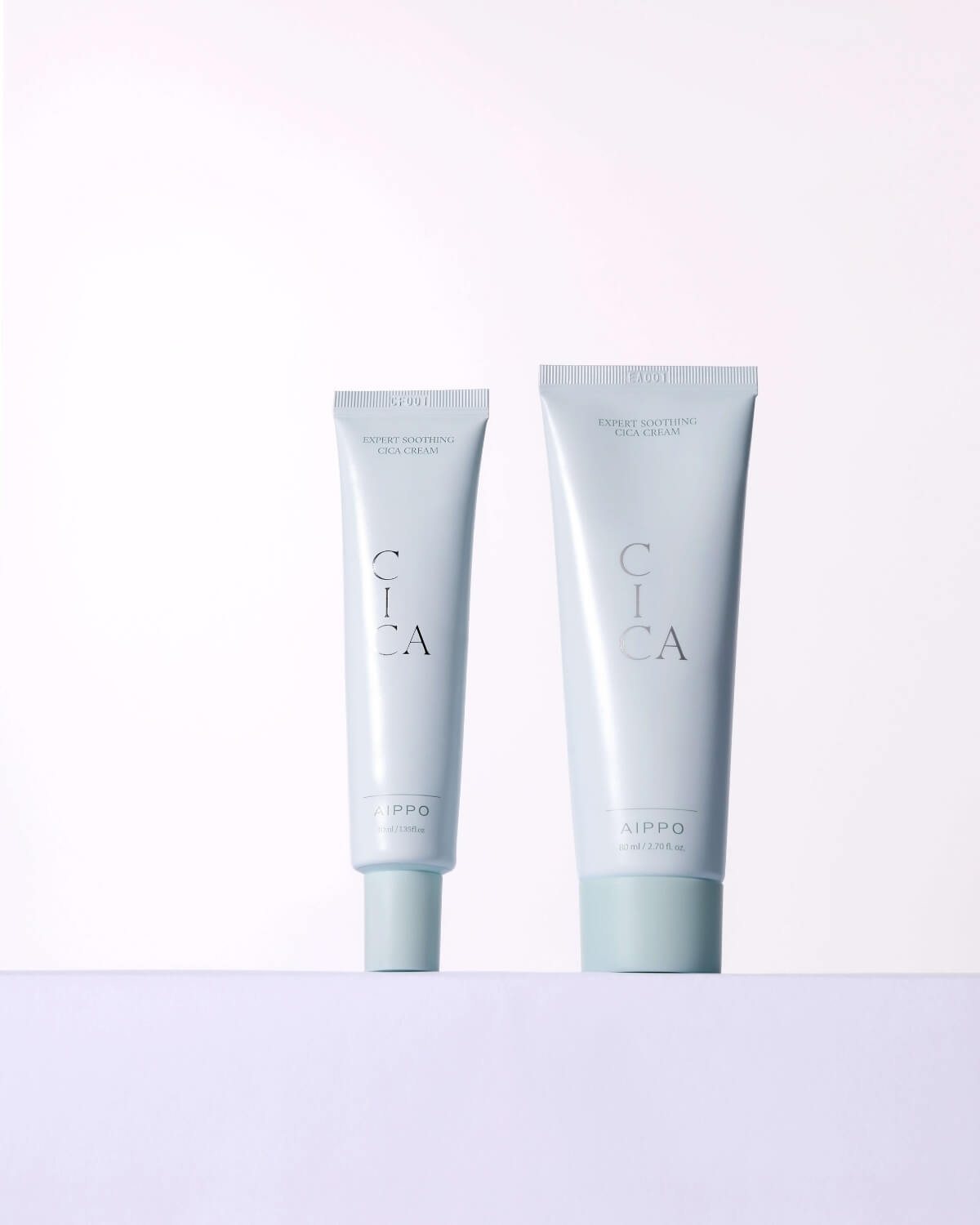 A side-by-side comparison of the two sizes of Aippo Expert Soothing Cica Cream tubes: the standard 40ml size and a larger tube, both featuring the signature cool-toned packaging.