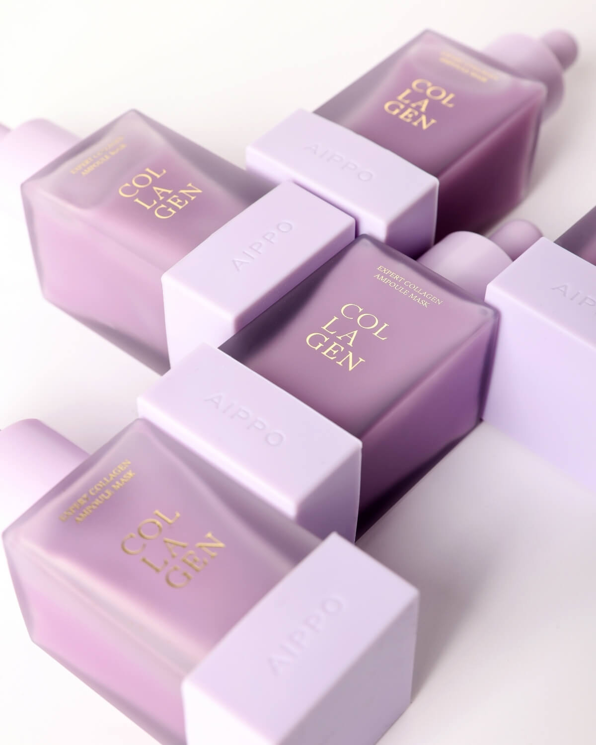 An overhead, angled view of multiple frosted purple Aippo Collagen Ampoule Mask bottles arranged in a diagonal pattern against a white background.