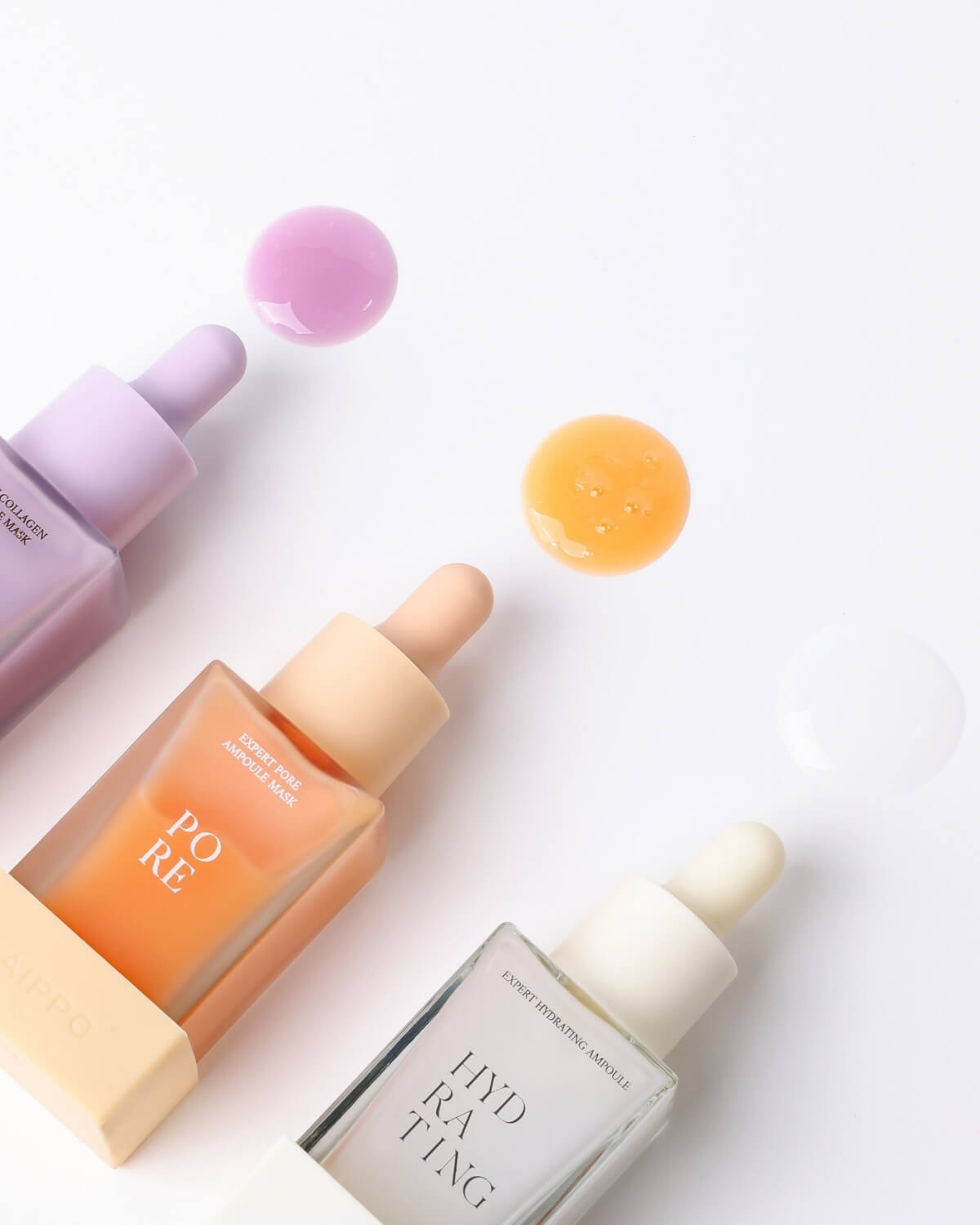 A clear dropper bottle of the Expert Hydrating Ampoule stands on a white surface, surrounded by droplets and a small pool of the blue liquid, emphasizing its fluid and watery nature.