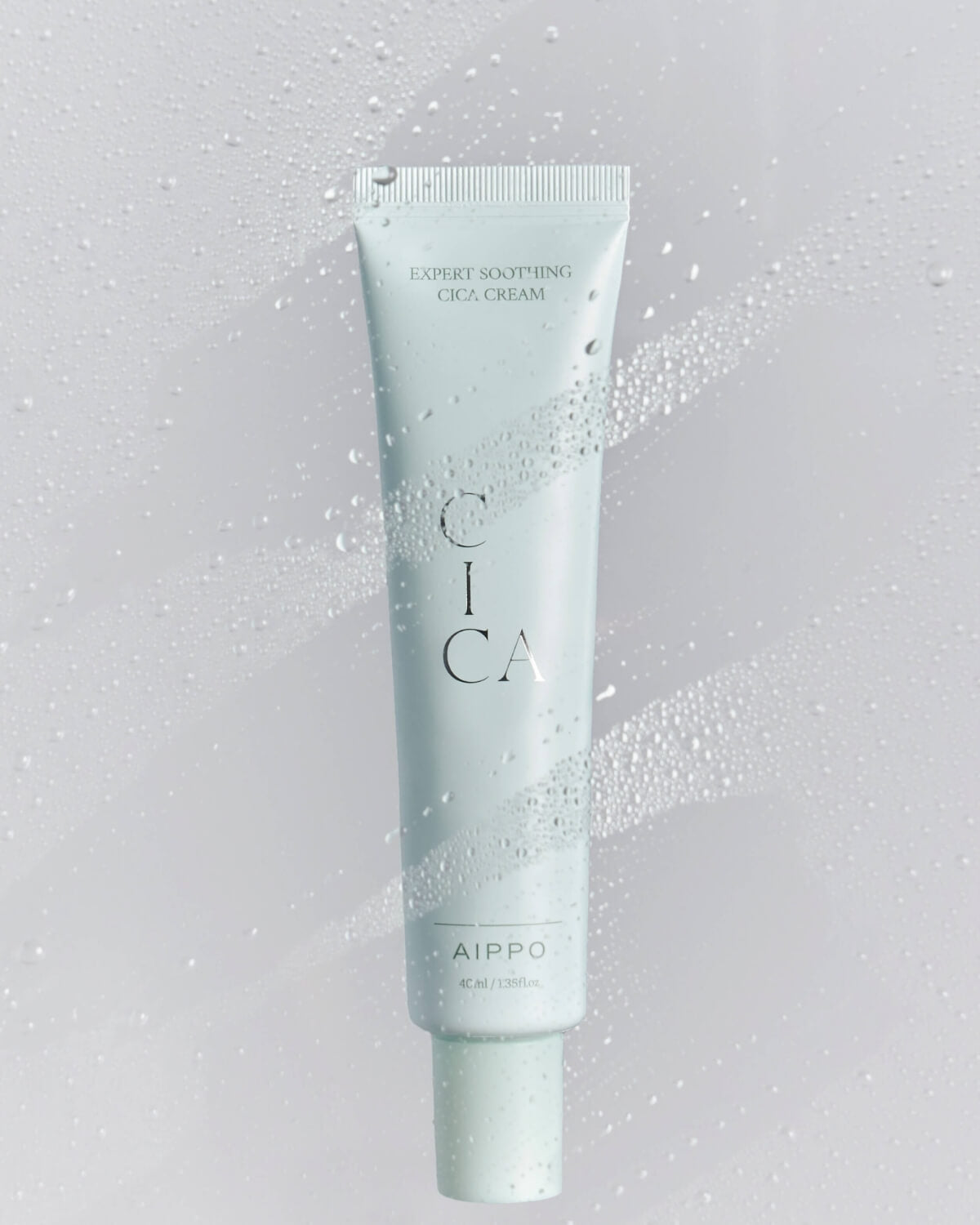The Cica Cream tube is featured against a gradient white background, covered with realistic water droplets, emphasizing the cream's soothing and hydrating properties.