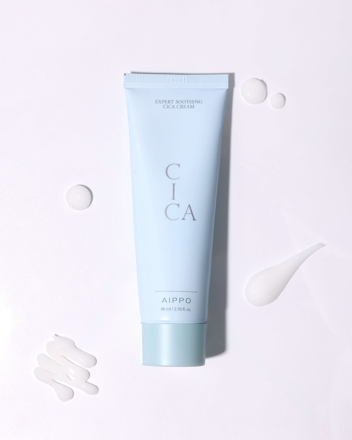 The Cica Cream tube is centered on a white surface, surrounded by various dollops and smears of the white cream product, demonstrating its texture and highlighting the clean, cool-toned packaging.