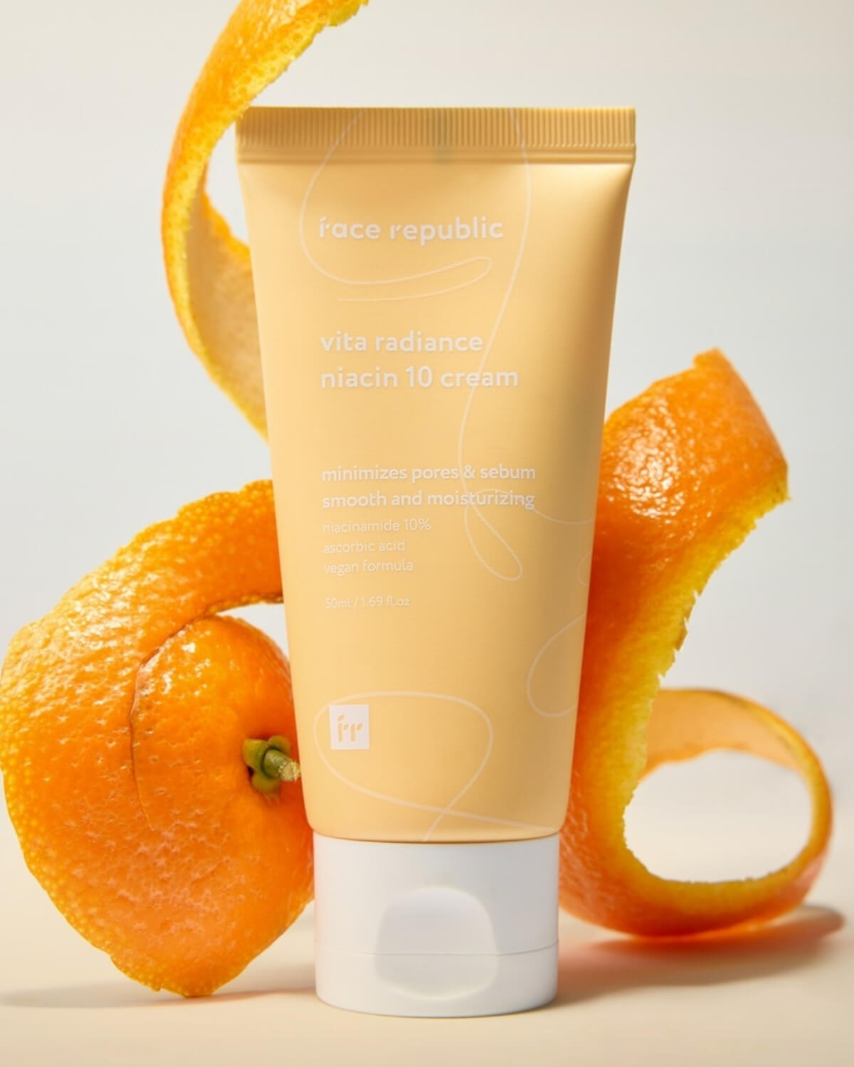 Face Republic Vita Radiance Niacin 10 Cream tube with fresh orange peels representing Vitamin C.