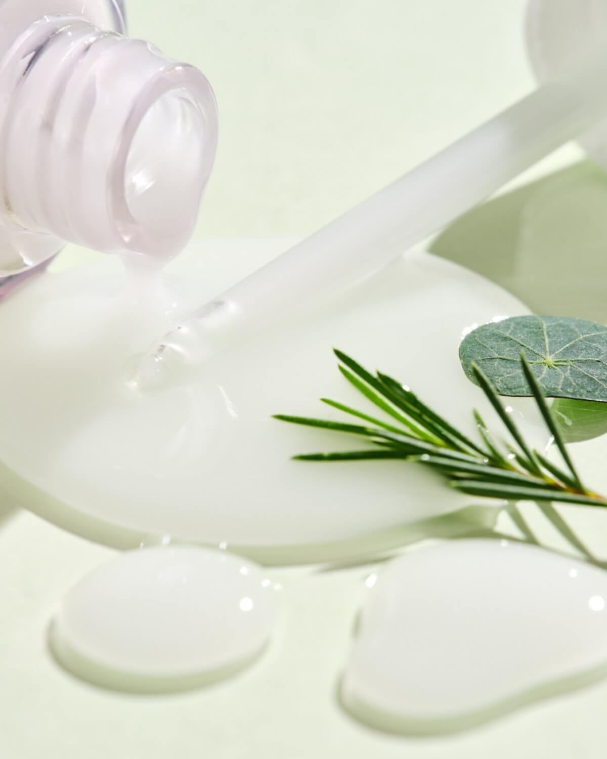 Close-up of the milky texture of Face Republic Madecassoside Serum with tea tree leaves.