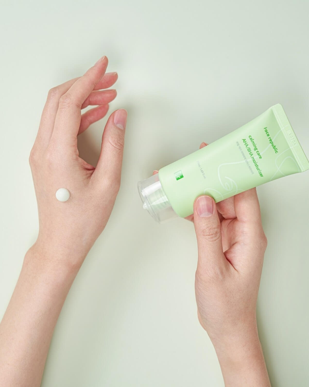 Person applying a small dot of green Face Republic AHA BHA moisturizer to the back of their hand.