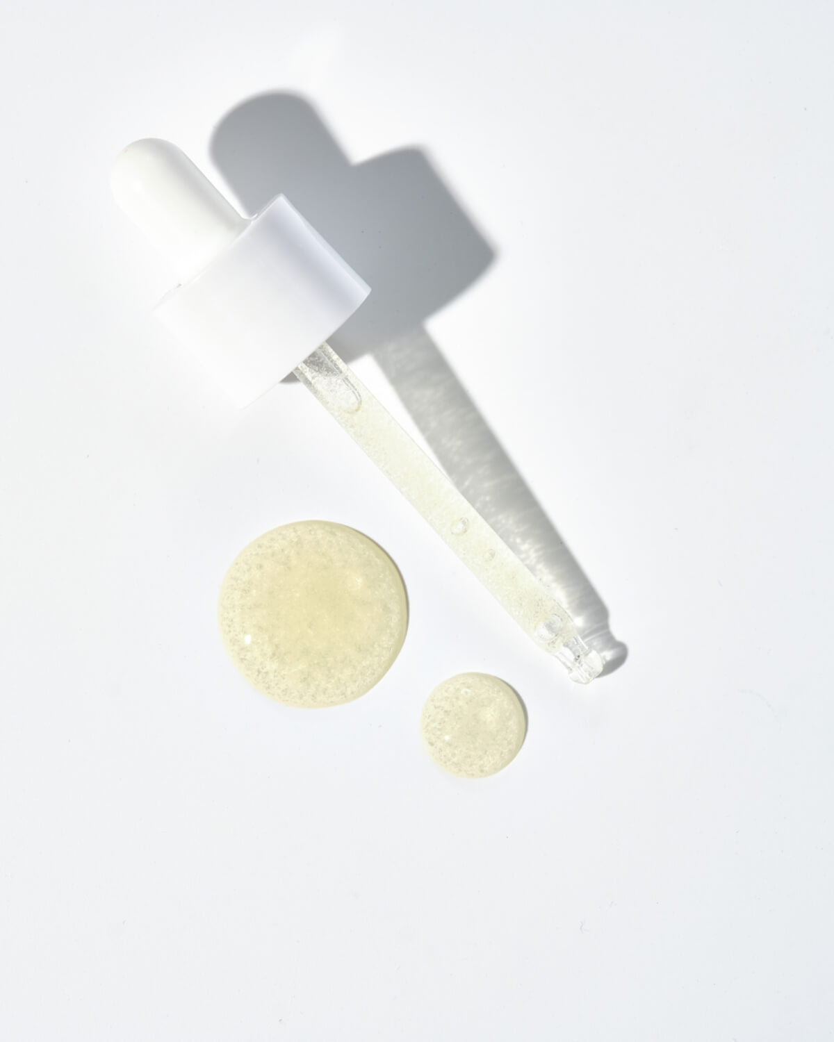 Close-up of serum texture showing revitalizing vitamin capsules on a white surface.