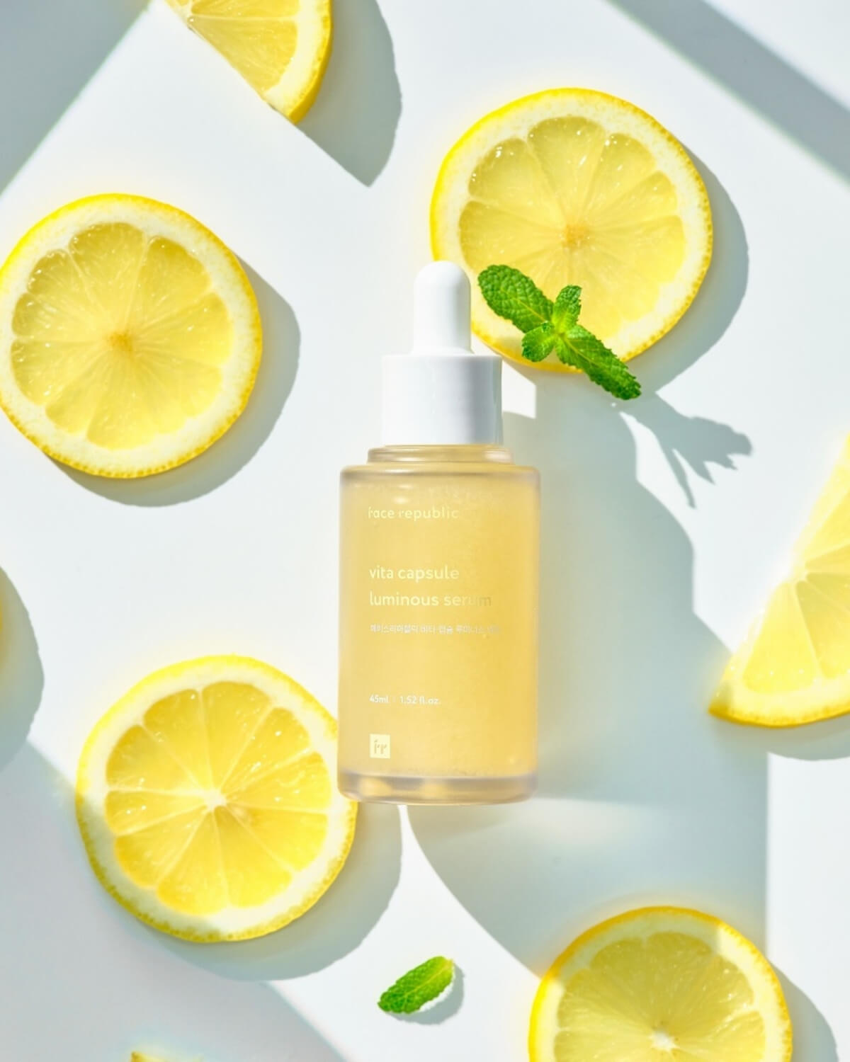 Face Republic Luminous Serum bottle surrounded by fresh lemon slices and mint.
