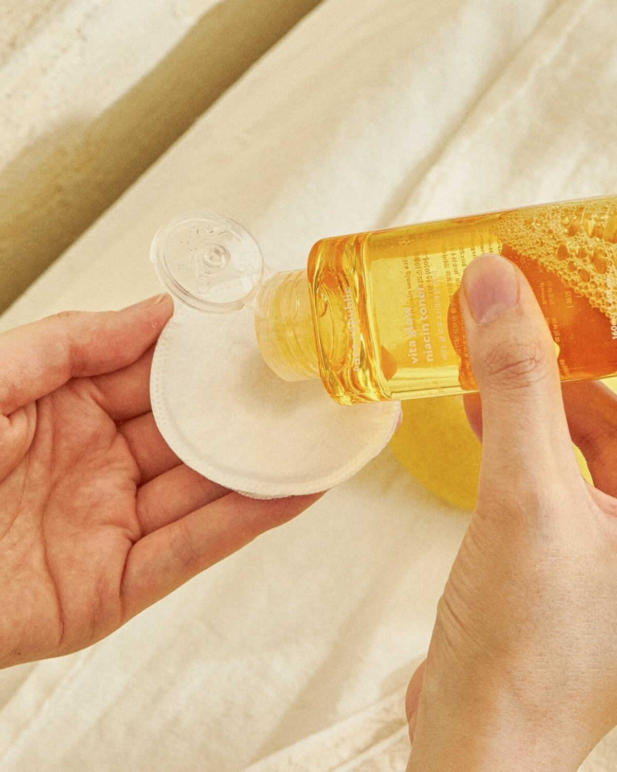 Close-up of applying Face Republic niacinamide toner to a cotton round.