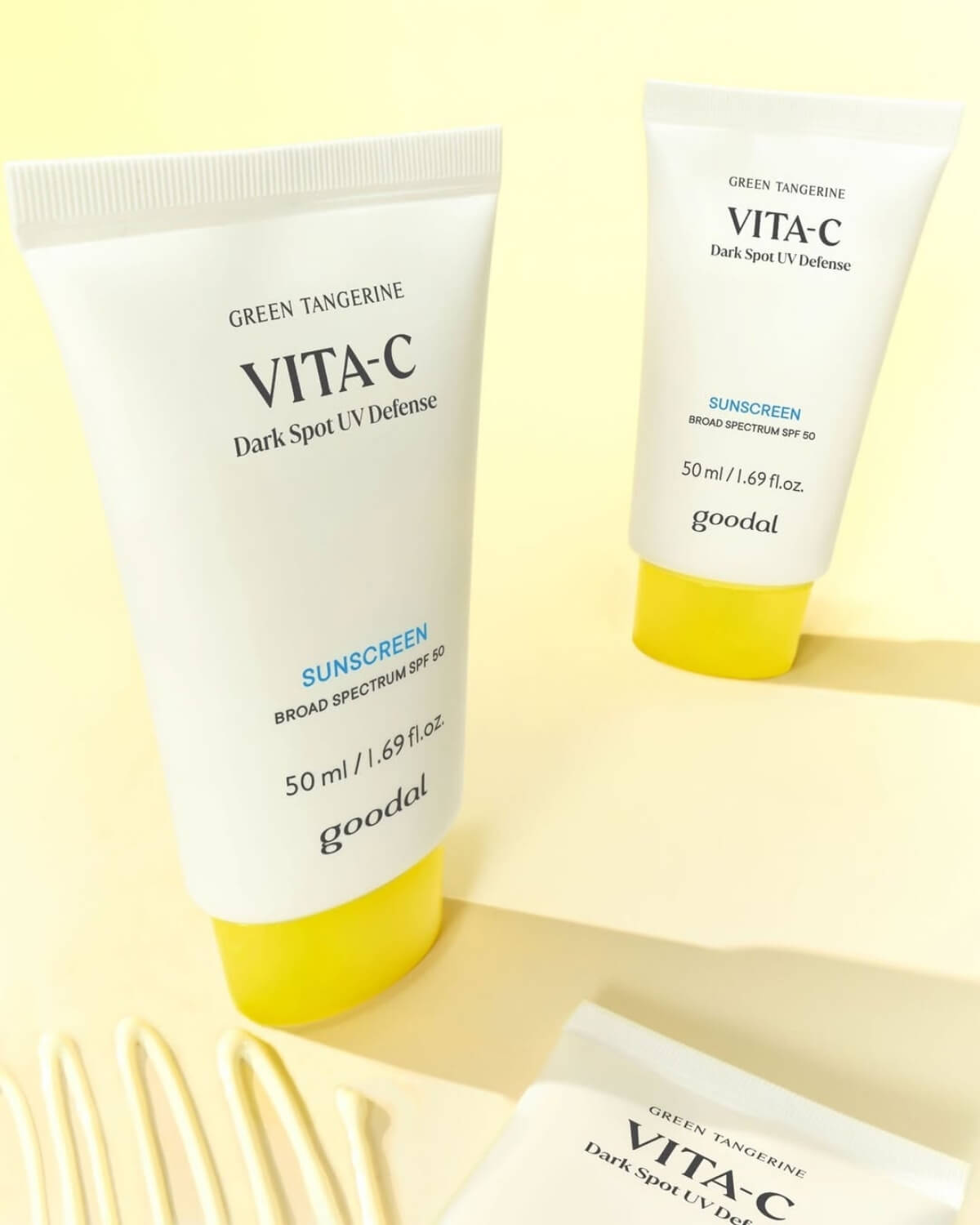 Flat lay of Goodal SPF 50 sunscreen tubes arranged on a soft yellow background with neat lines of squeezed cream texture