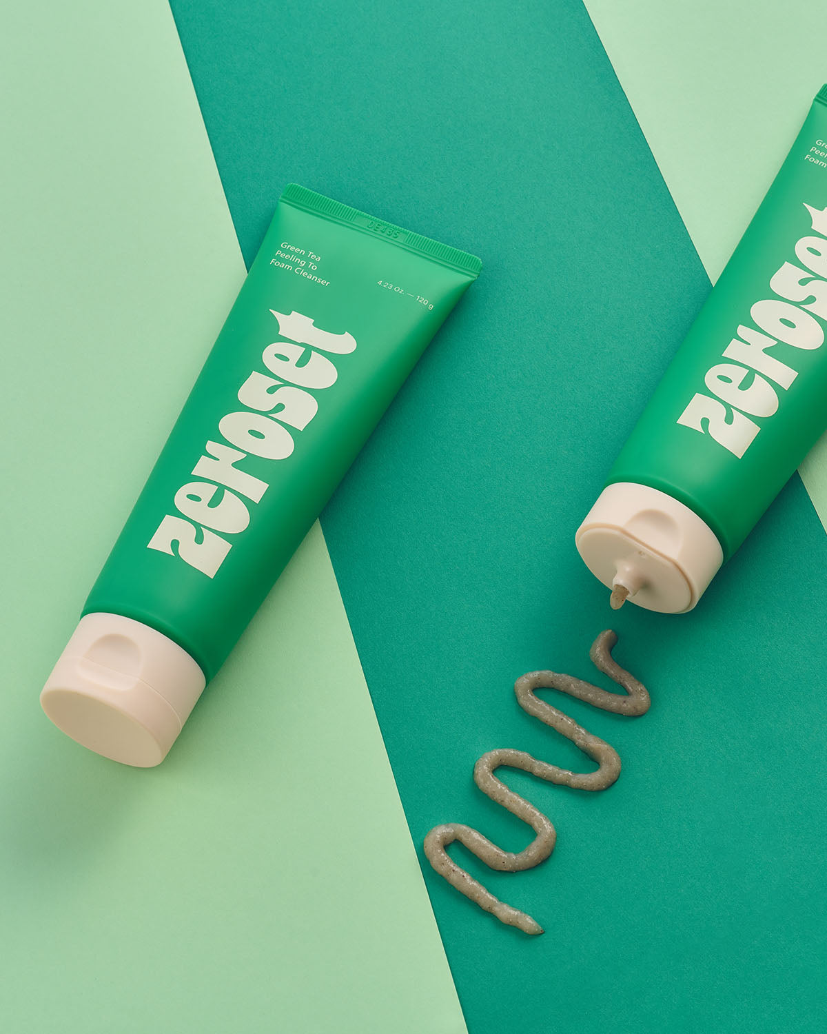 Two green tubes of Zeroset green tea peeling to foam cleanser with a gel strip on a green background.