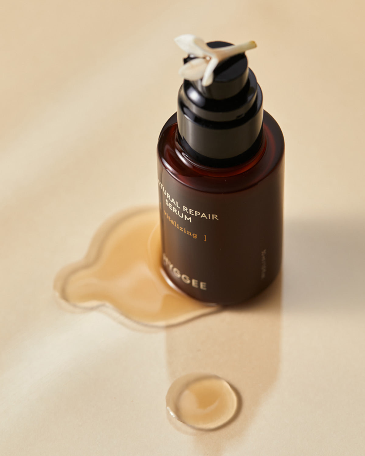Close-up of Natural Repair Serum bottle and a drop of the brown liquid. Ginseng energy serum for vitalizing and root hydration.