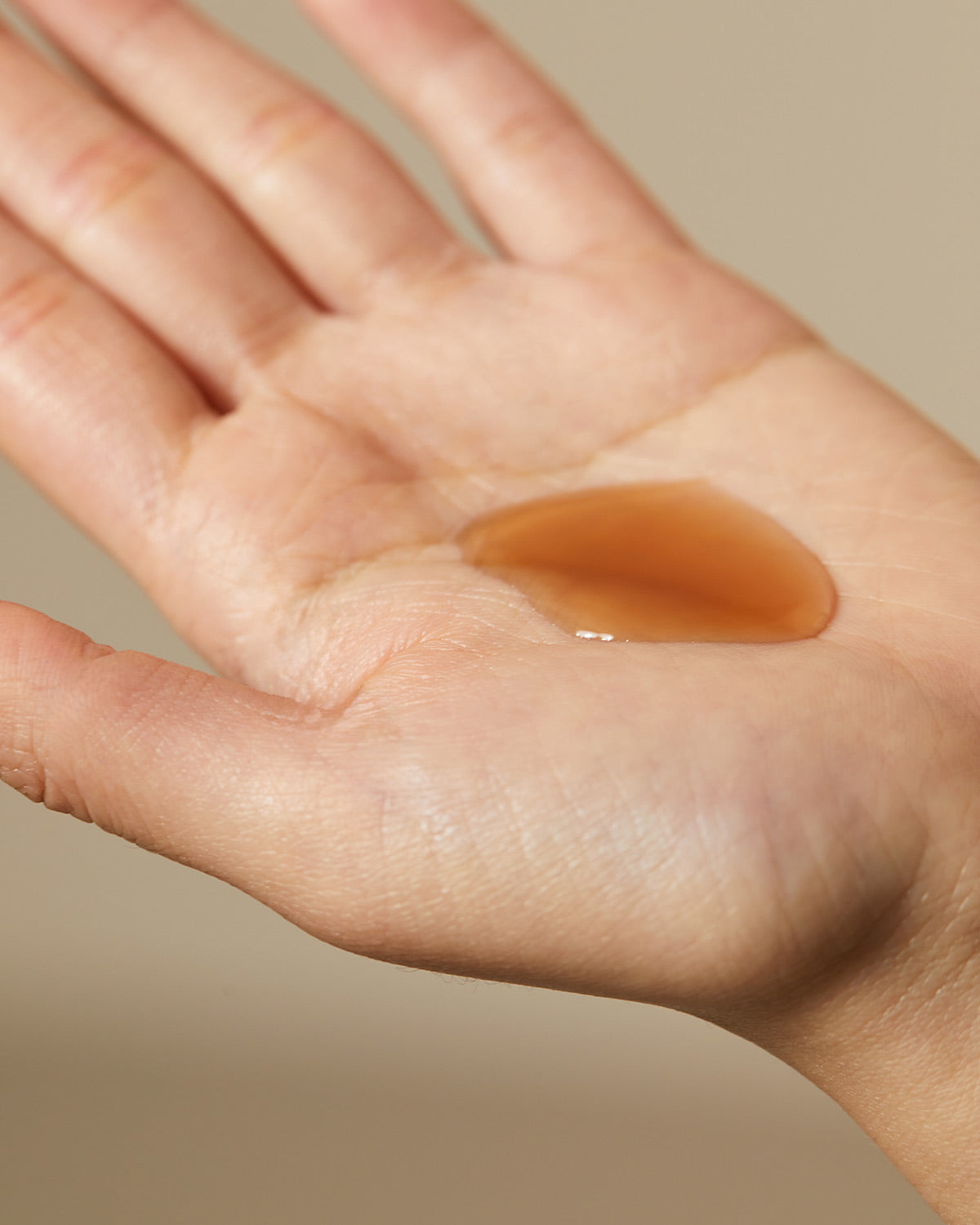 Hand holding a drop of the Hyggee Natural Repair Serum. Vitalizing ginseng serum for recharging skin with hydration and energy.