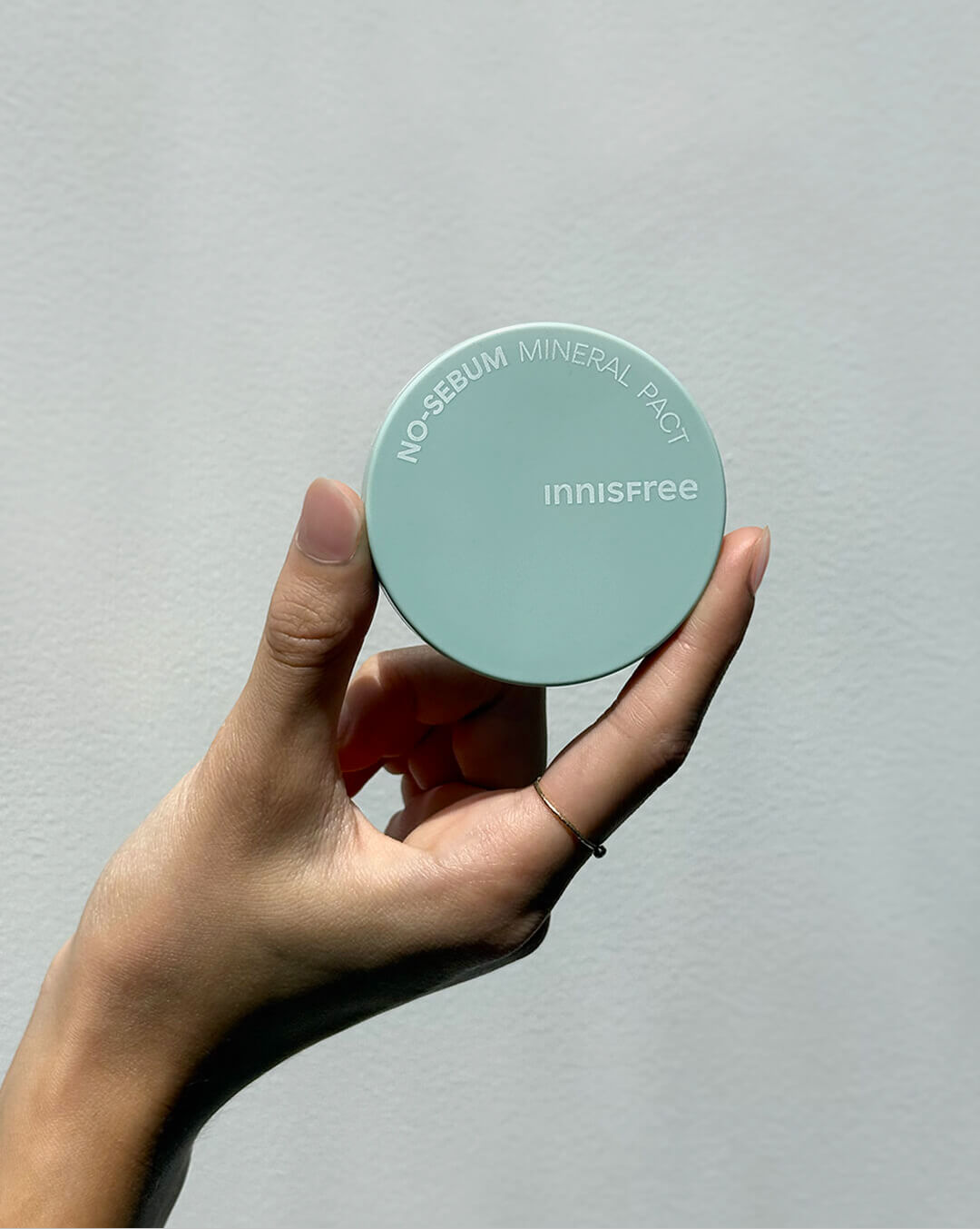 Hand holding a mint Innisfree No Sebum Mineral Pact. Oil control setting powder for a matte finish. Korean beauty staple.