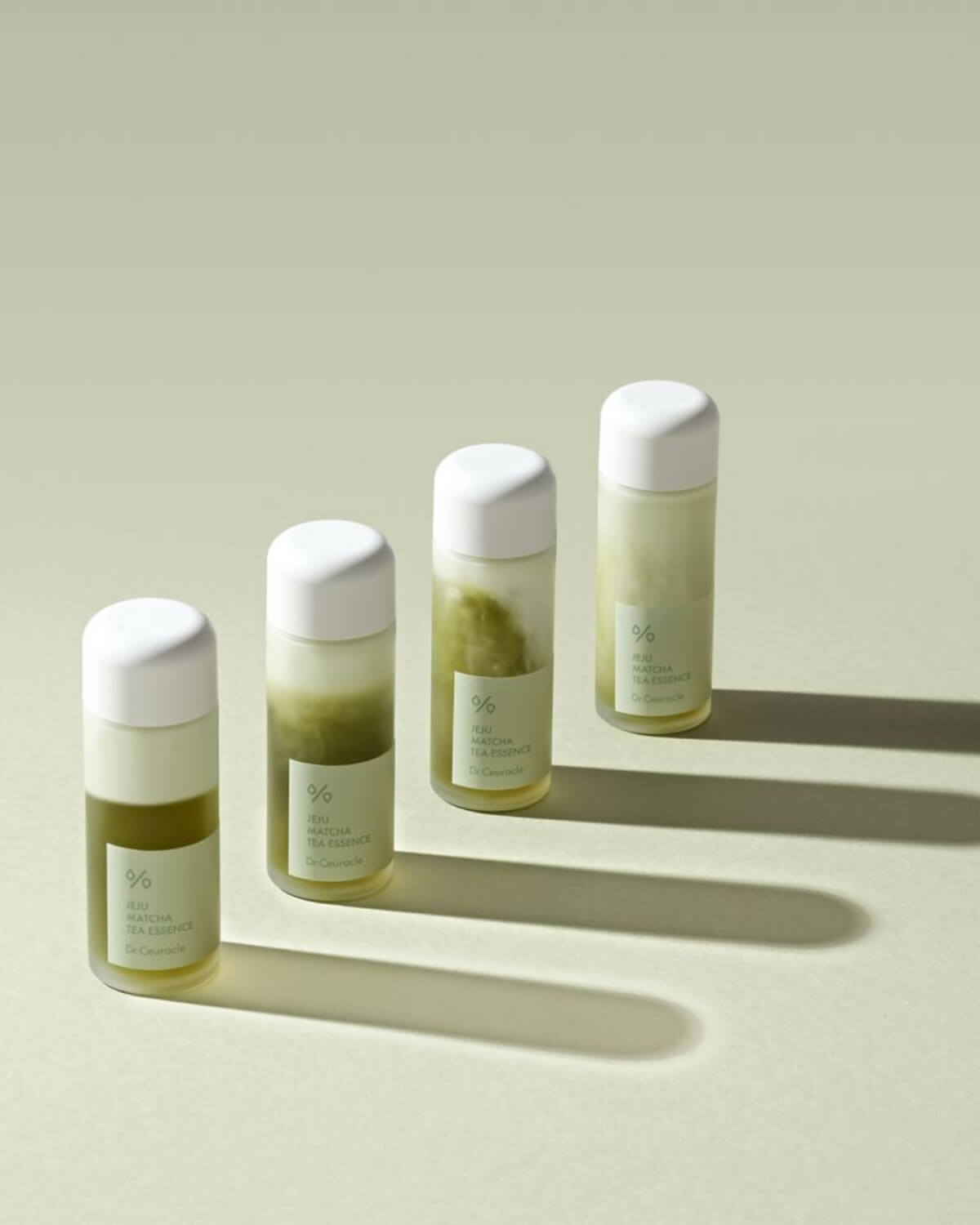 Four bottles of Dr. Ceuracle Jeju Matcha Tea Essence lined up to show the mixing process of the bi-phase formula.