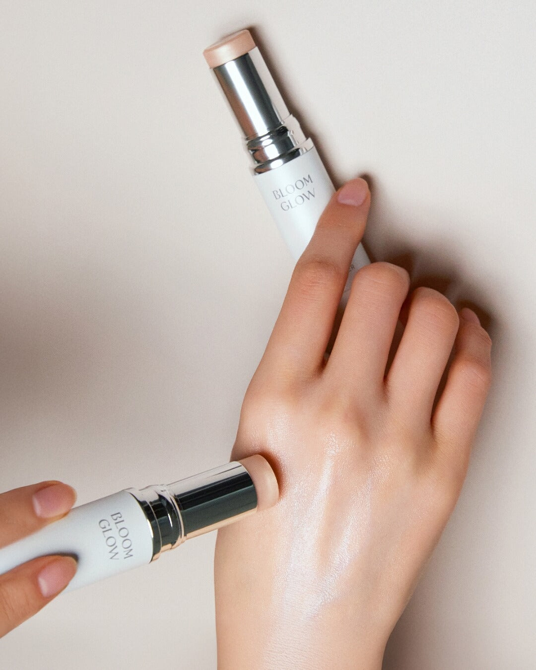 Close-up of a person applying the Koy Bloom Glow Stick Highlighter to the back of their hand for a luminous sheen.