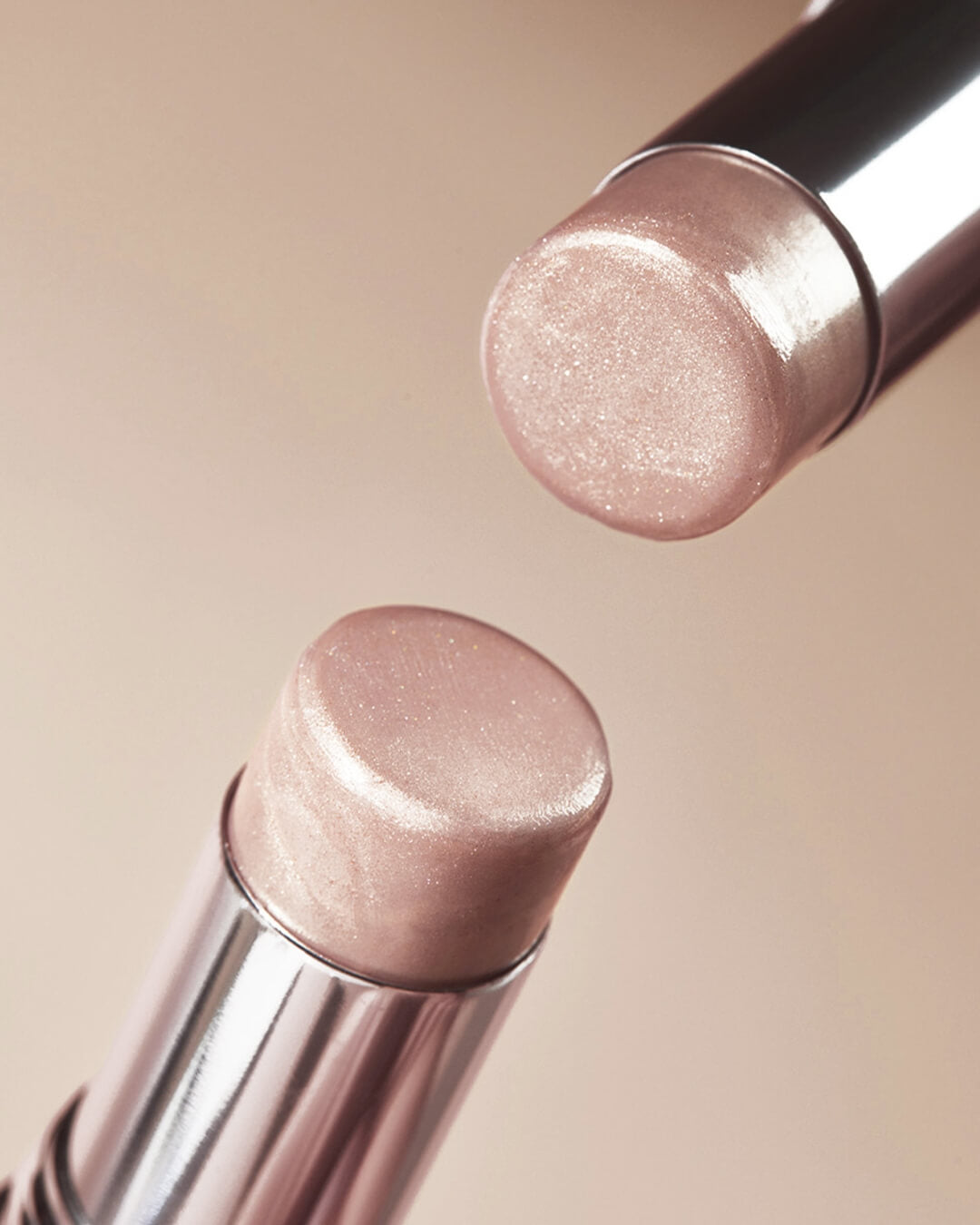Top-down close-up of two open Koy Bloom Glow Stick Highlighters showcasing the glittering texture of the balm.
