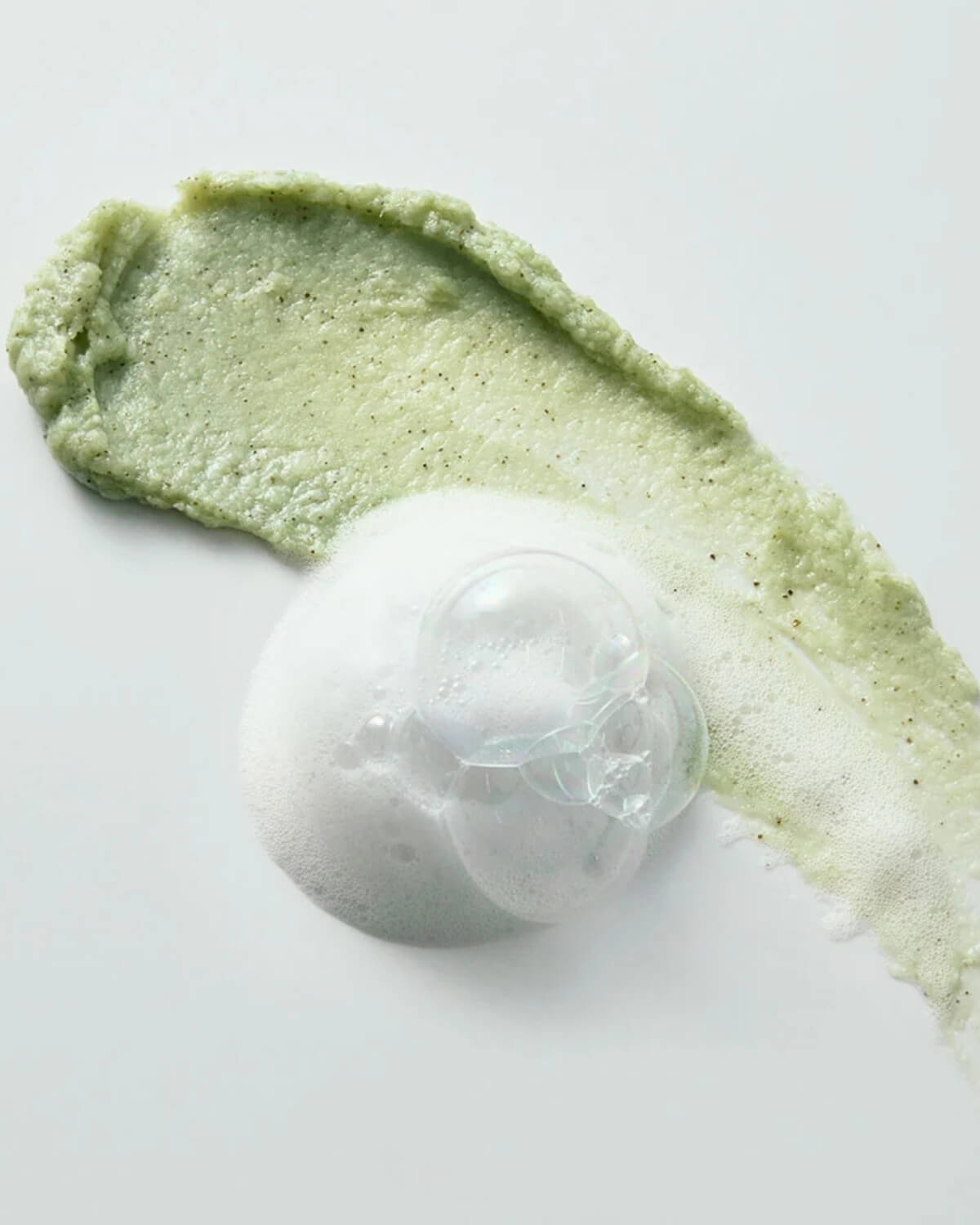 Green matcha mask paste swatch lathering into rich white cleansing foam on a plain background.
