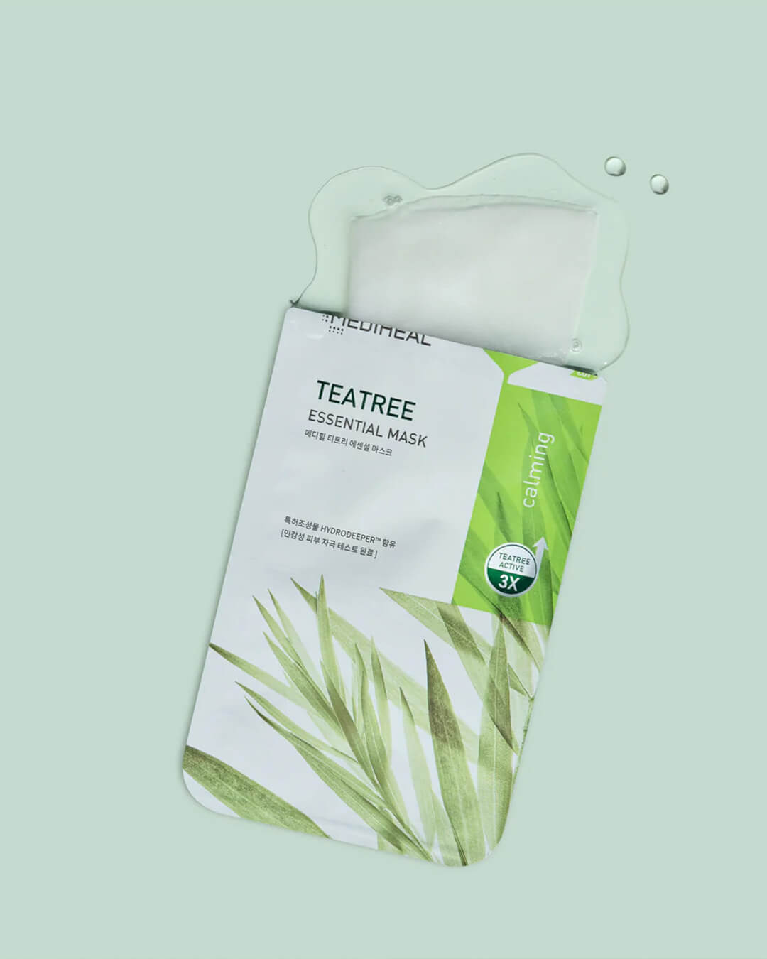 Mediheal Tea Tree Essential Mask_Intensive Calming & Clarifying Mask, product on a green background showing the mask texture soaked in essence