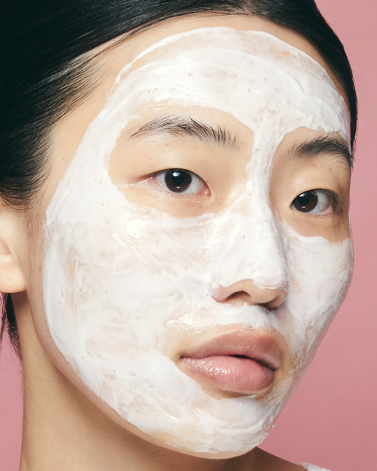 Close-up of a woman's face covered in a thick layer of white Purito Multi PDRN Collagen Real Glow Mask.