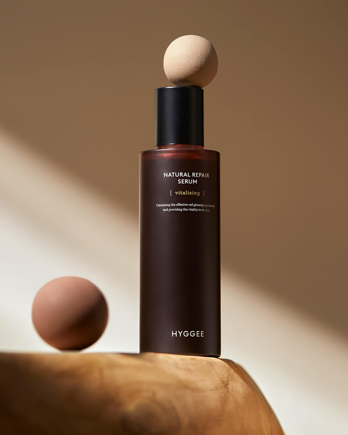 Full bottle of HYGGEE Natural Repair Serum vitalizing essence on wood. Red ginseng for glowing, vital skin.