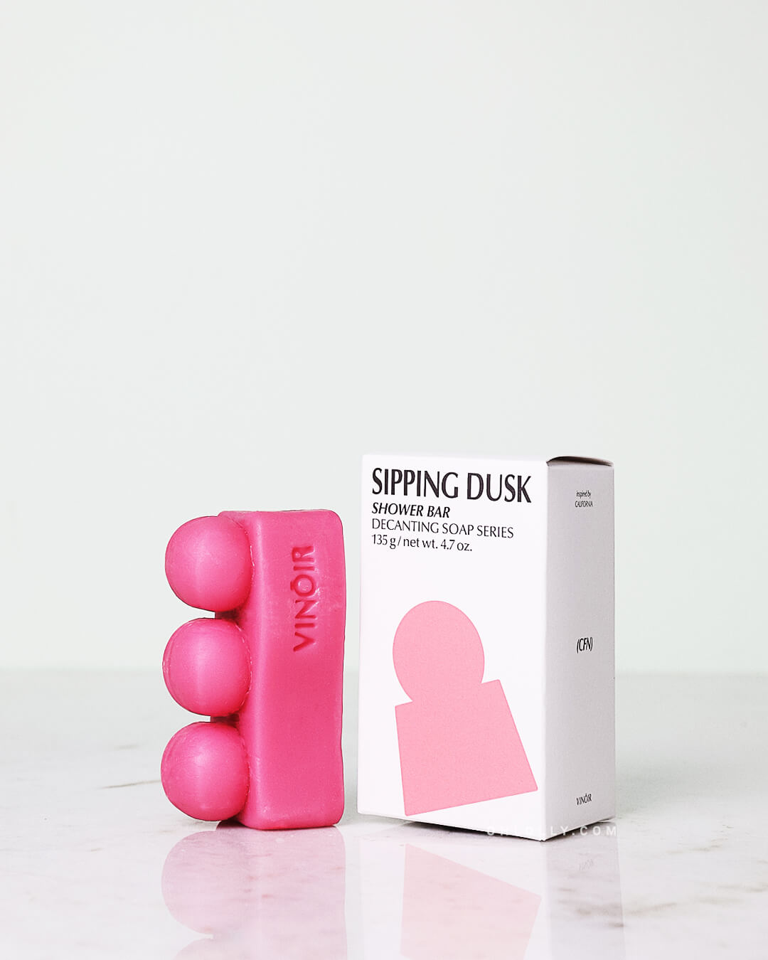 Pink soap bar with packaging on a white background