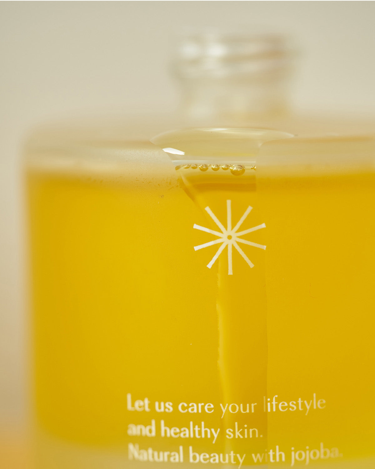 Close-up of Pinkwonder Jojoba Oil dropper releasing golden oil into the bottle, emphasizing purity and smooth texture.