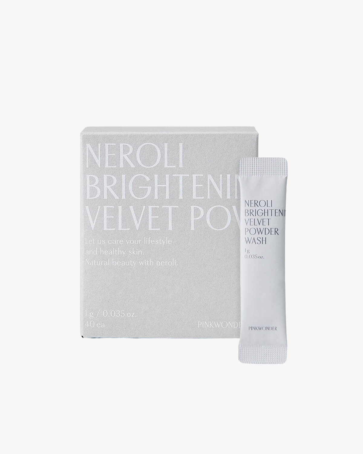 A centered product shot showing the square, light gray box for the "Neroli Brightening Velvet Powder Wash" next to a single, white, stick-pack sachet of the powder wash.