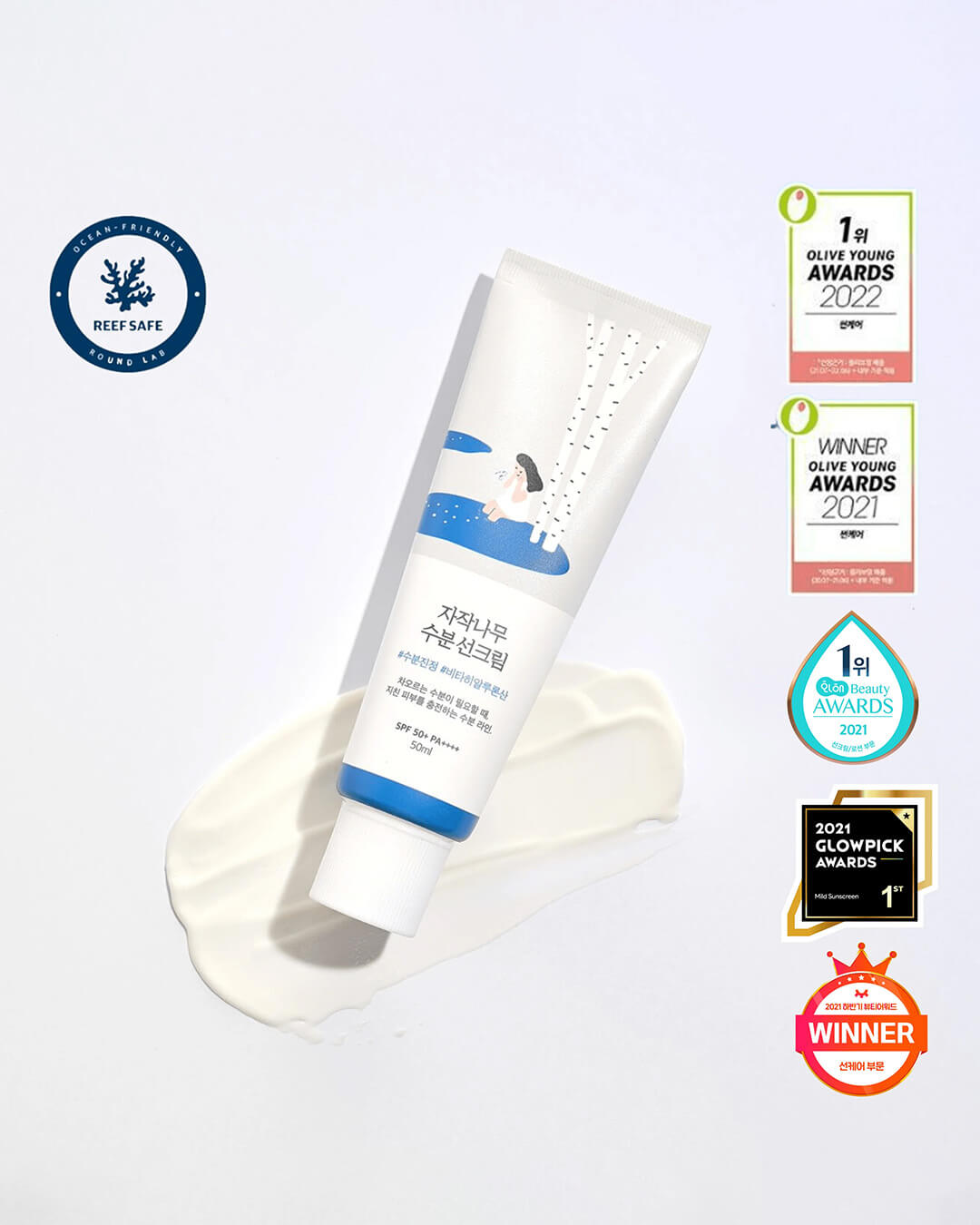 A white tube of Round Lab Birch Moisturizing Sun Cream is pictured on a swirl of the white sunscreen product, surrounded by various Korean and global beauty awards seals (Olive Young, Glowpick) and a 'Reef Safe' emblem.