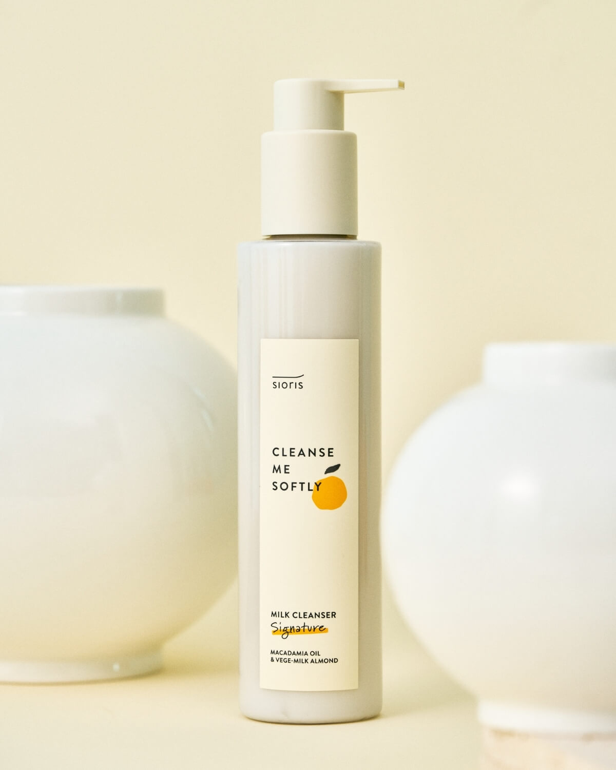 Sioris cleanser bottle centered between two white ceramic vases.