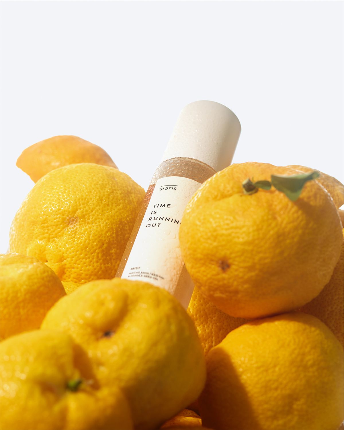 Sioris Time is Running Out_All-in-One Nourishing Oil Mist Toner bottle on a mound of yuja fruits
