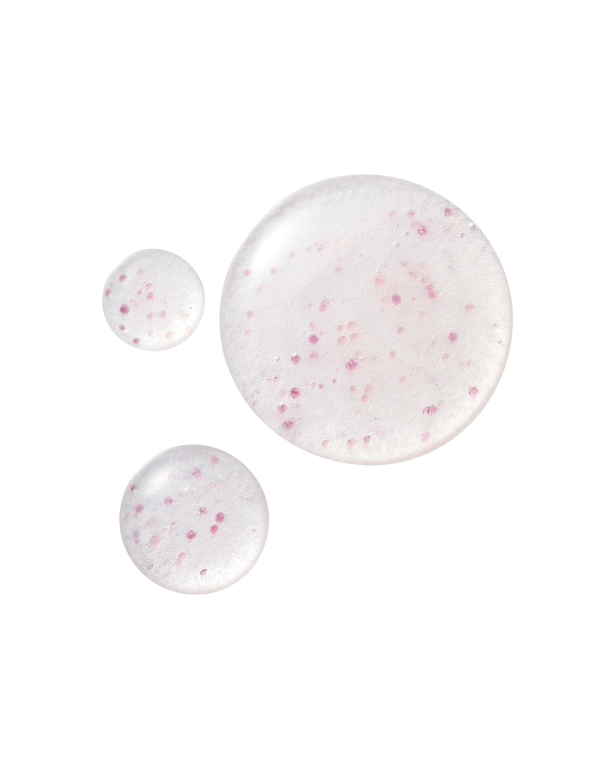 Three droplets of clear serum containing suspended pink capsules of varying sizes on a white background.